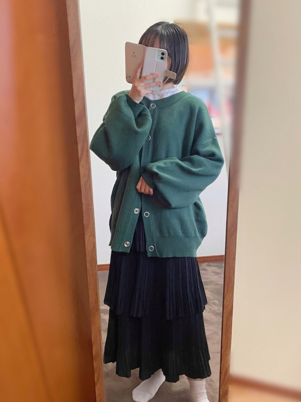 グリーン系のカーディガン/ボレロ、ブラック系のスカート、ブラック系のパンプスを着用したレディースの冬コーディネートの1枚目の写真