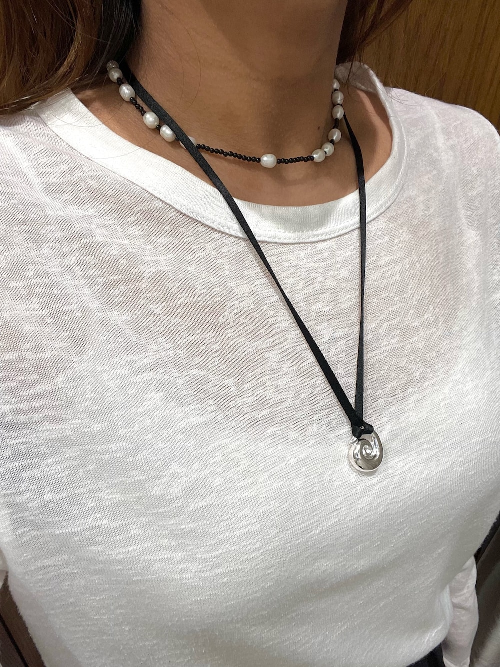 シルバー系のネックレス、ブラック系のネックレスを着用したレディースの春コーディネートの1枚目の写真