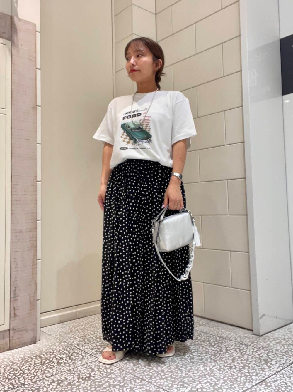 ホワイト系のサンダル、ホワイト系のTシャツ/カットソー、ブラック系のスカートを着用したレディースの夏コーディネートの1枚目の写真