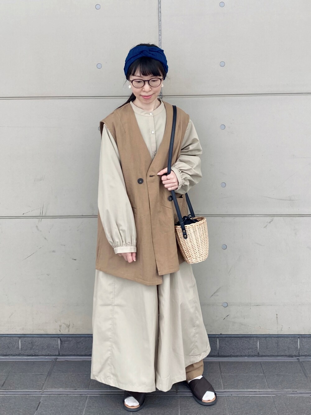 ベージュ系のシャツワンピース、ベージュ系のベスト、ブラック系のハンドバッグを着用したレディースの春コーディネートの1枚目の写真