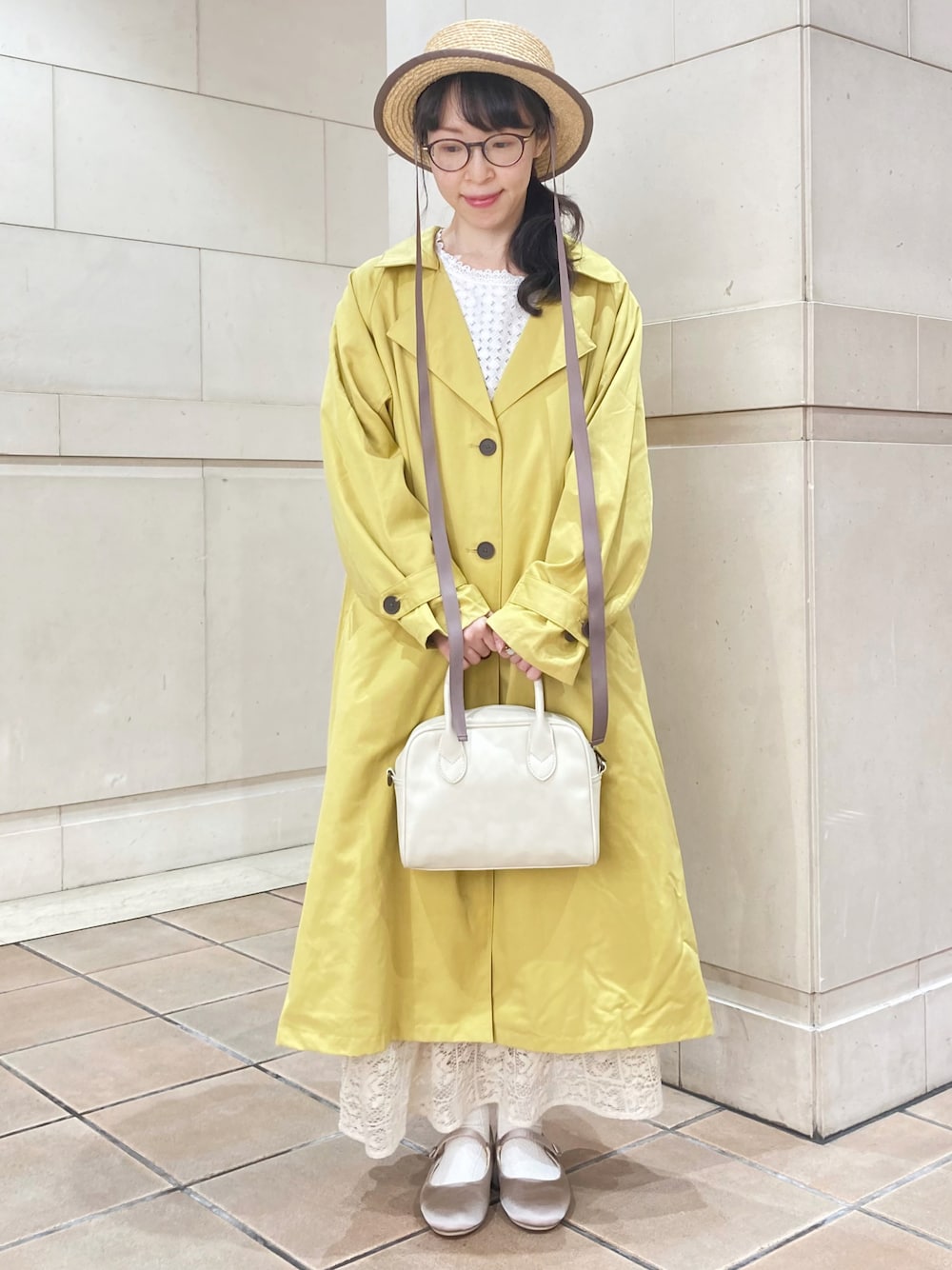 イエロー系のトレンチコート、ホワイト系のショルダーバッグ、ベージュ系のその他シューズを着用したレディースの春コーディネートの1枚目の写真