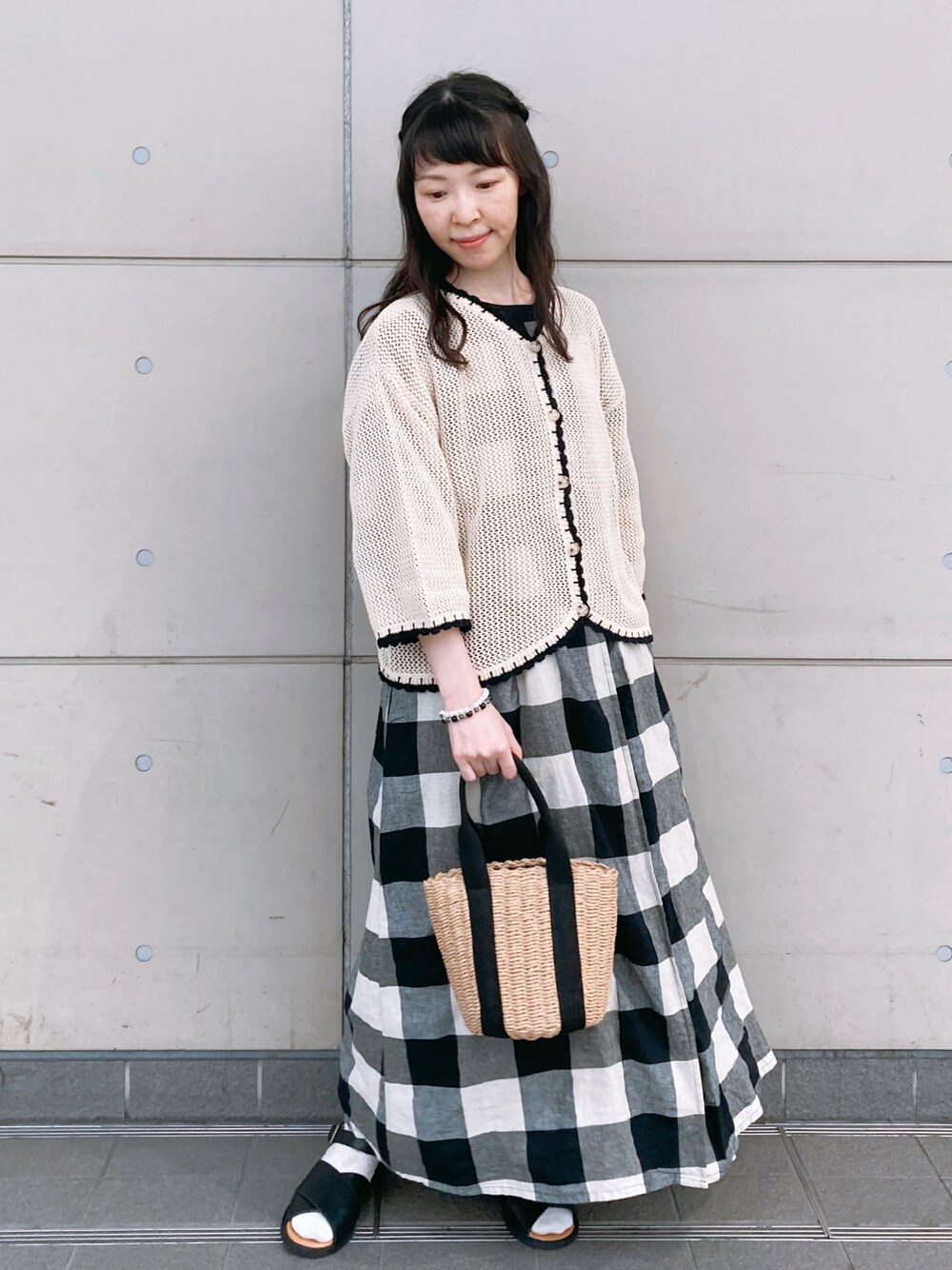 ブラック系のハンドバッグ、ホワイト系のカーディガン/ボレロ、ブラック系のワンピースを着用したレディースの春コーディネートの1枚目の写真