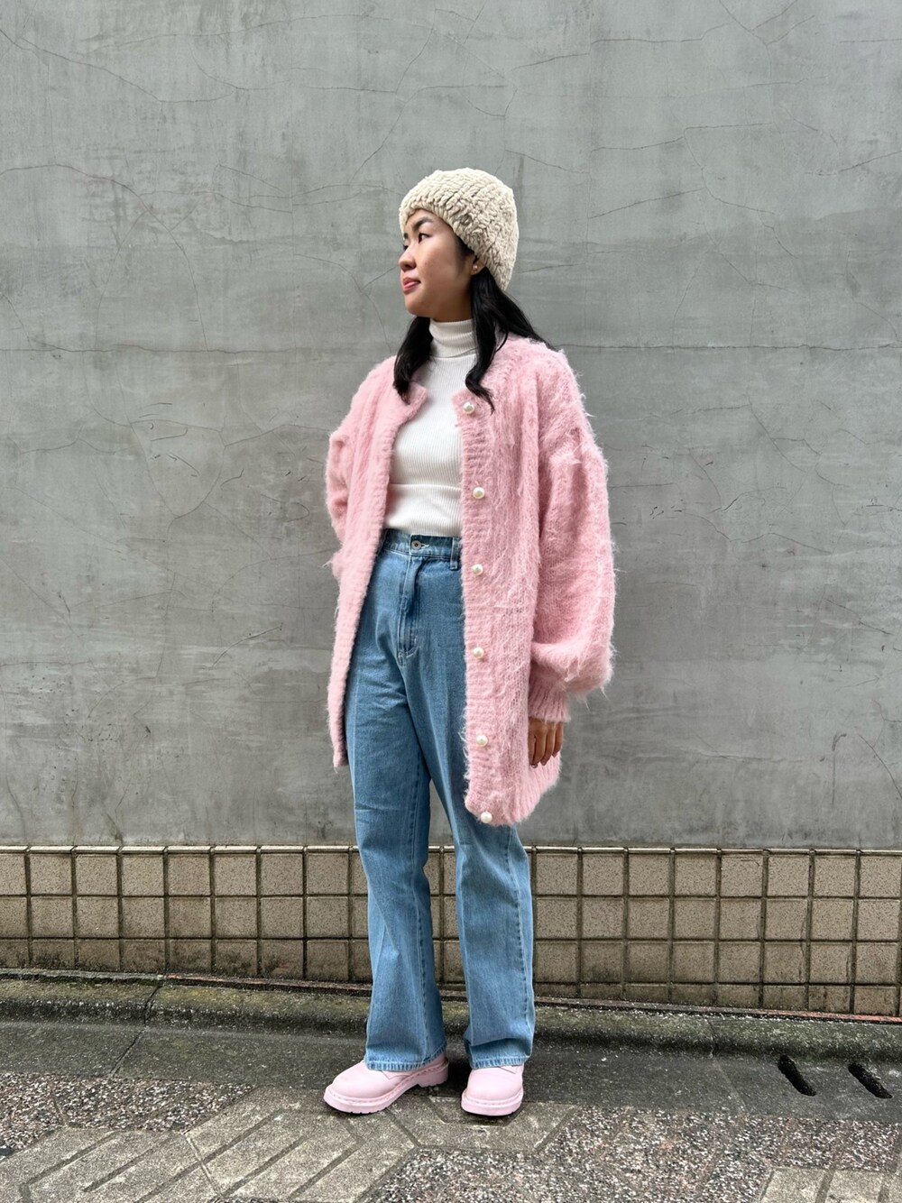 ピンク系のカーディガン/ボレロ、ブルー系のデニムパンツ、ピンク系のブーツを着用したレディースの冬コーディネートの1枚目の写真