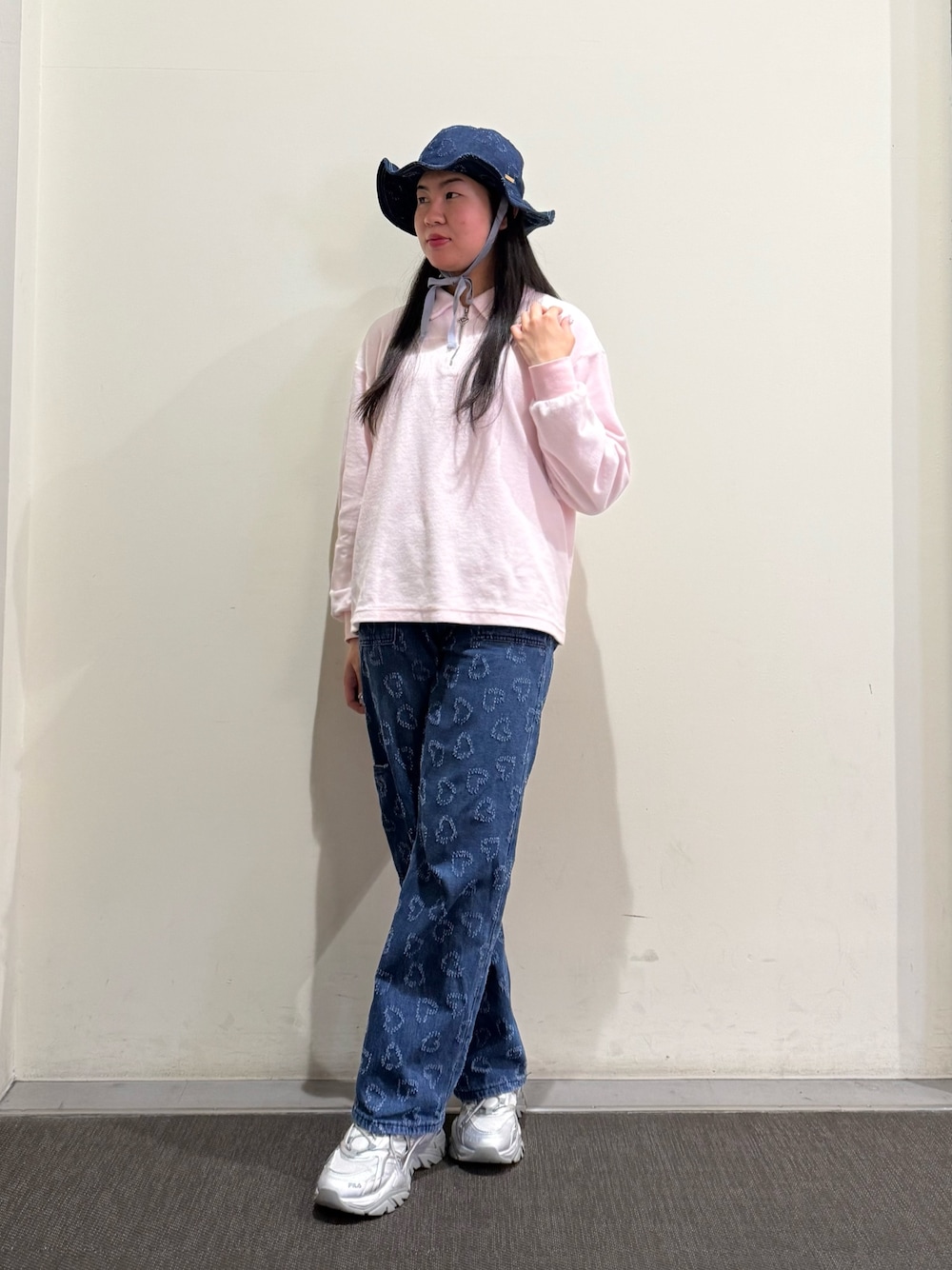 ピンク系のスウェット、ブルー系のデニムパンツ、グレー系のスニーカーを着用したレディースの春コーディネートの1枚目の写真