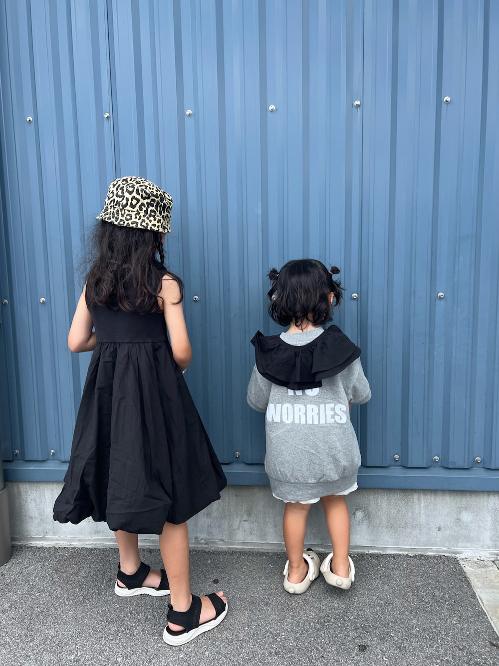 ブラック系のワンピース、グレー系のTシャツ/カットソー、ベージュ系のサンダルを着用したキッズの夏コーディネートの1枚目の写真