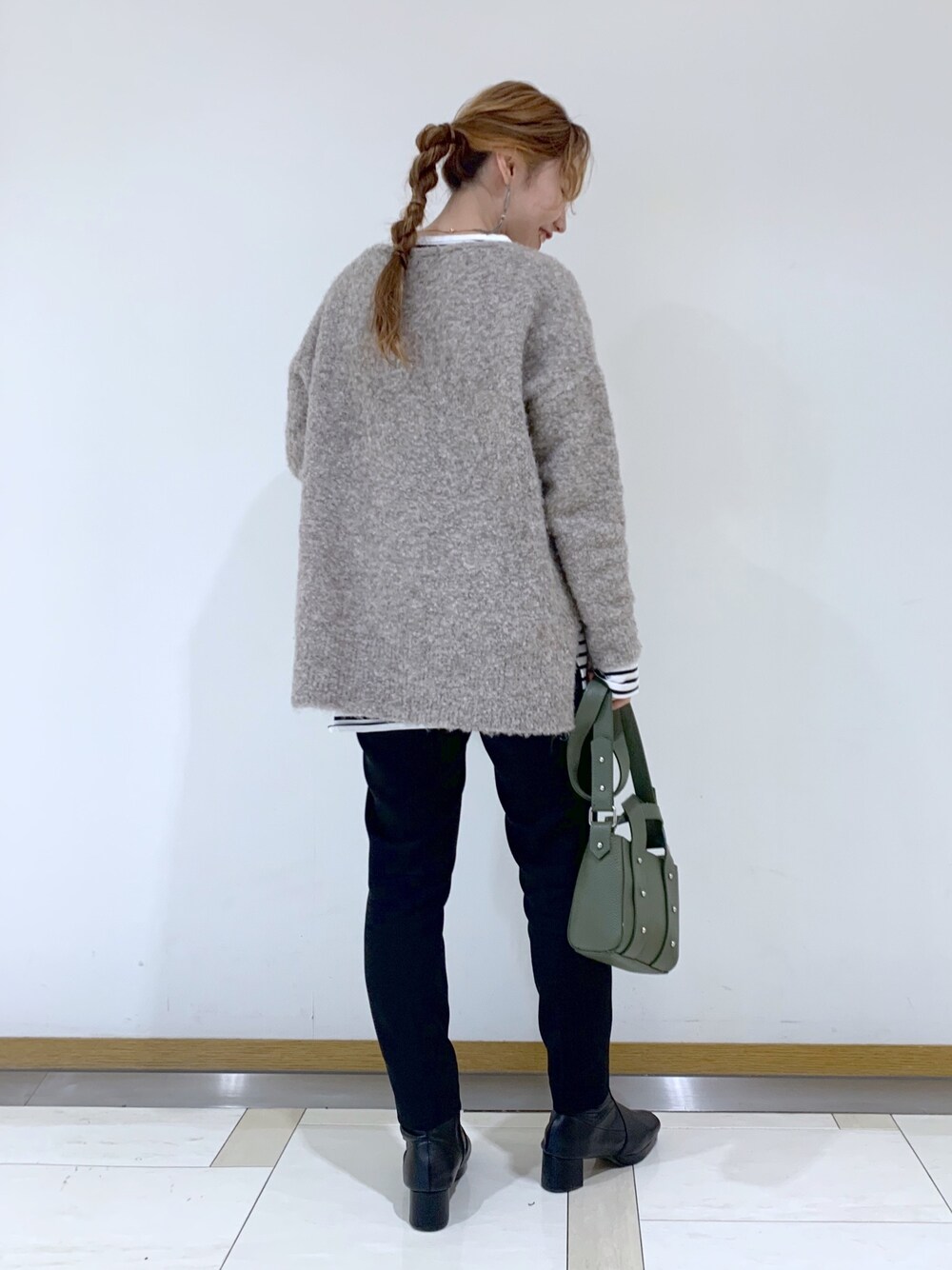 ベージュ系のニット/セーター、ホワイト系のTシャツ/カットソー、グリーン系のショルダーバッグを着用したレディースの冬コーディネートの2枚目の写真