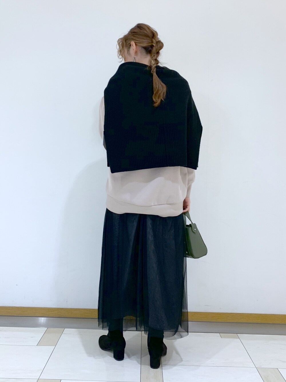 グレー系のトップス、ブラック系のニット/セーター、グリーン系のショルダーバッグを着用したレディースの冬コーディネートの2枚目の写真