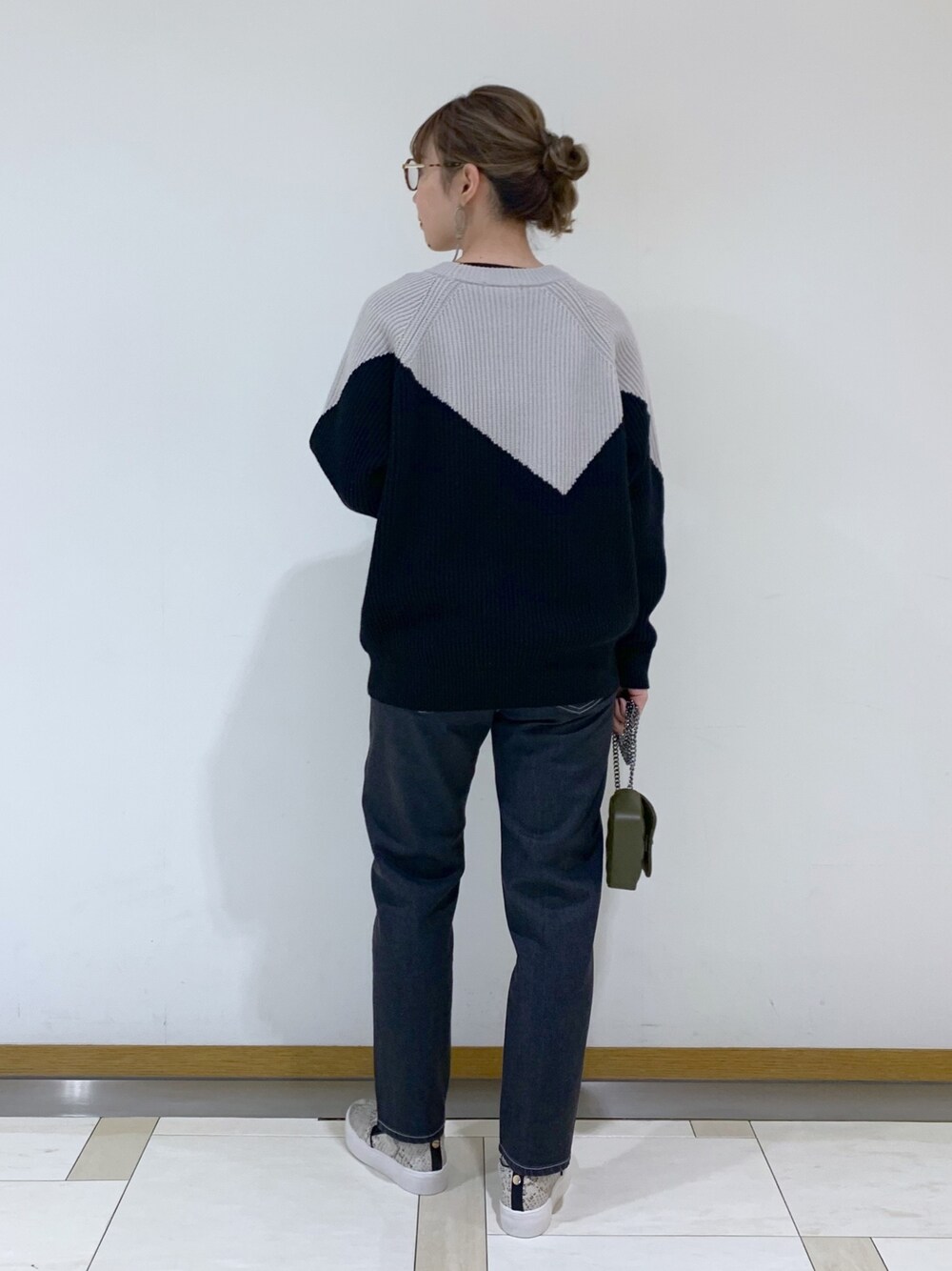 ブラック系のトップス、グレー系のデニムパンツ、グリーン系のショルダーバッグを着用したレディースの冬コーディネートの2枚目の写真