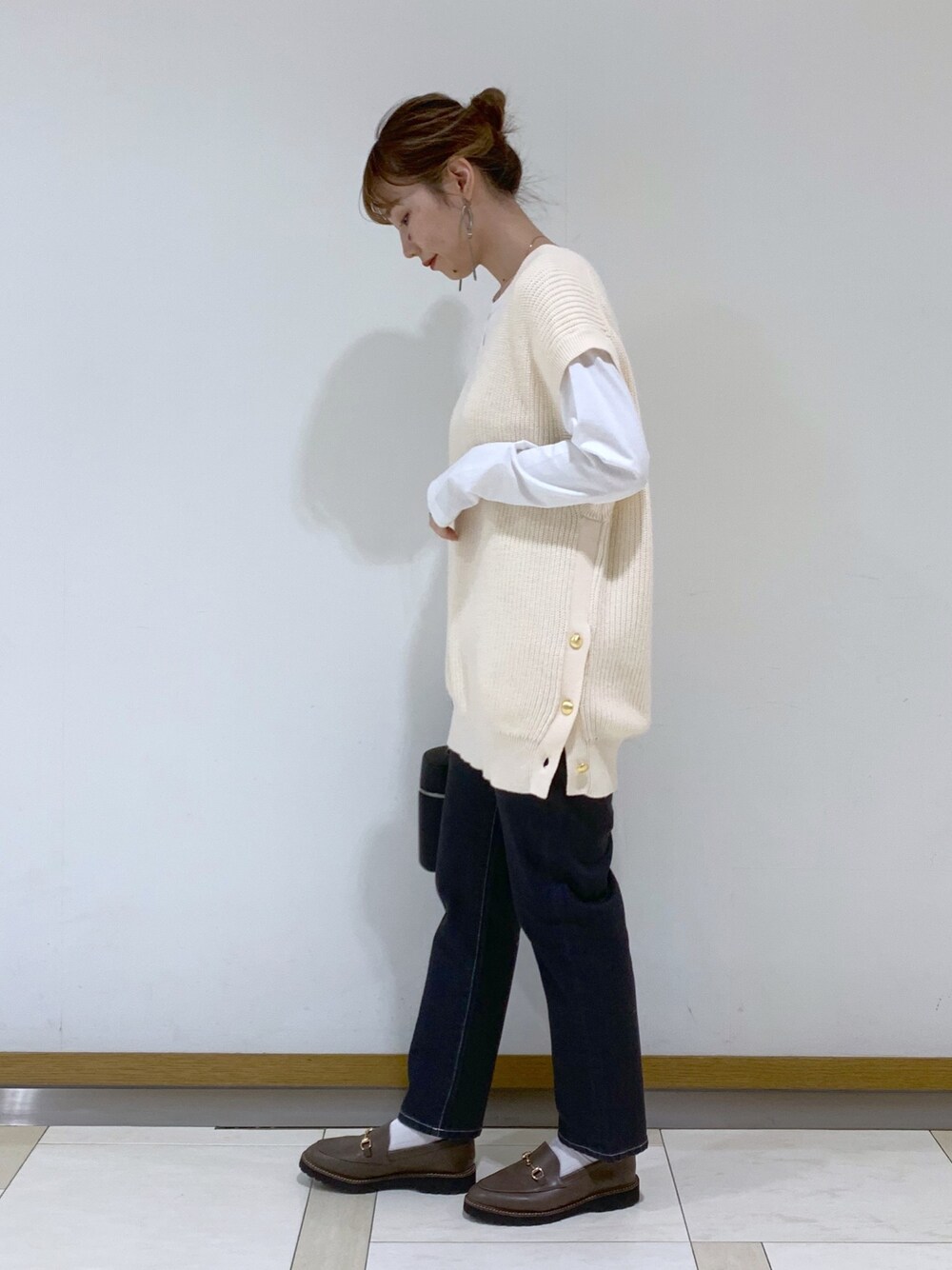 ホワイト系のトップス、ホワイト系のTシャツ/カットソー、ブラウン系のバッグを着用したレディースの冬コーディネートの2枚目の写真
