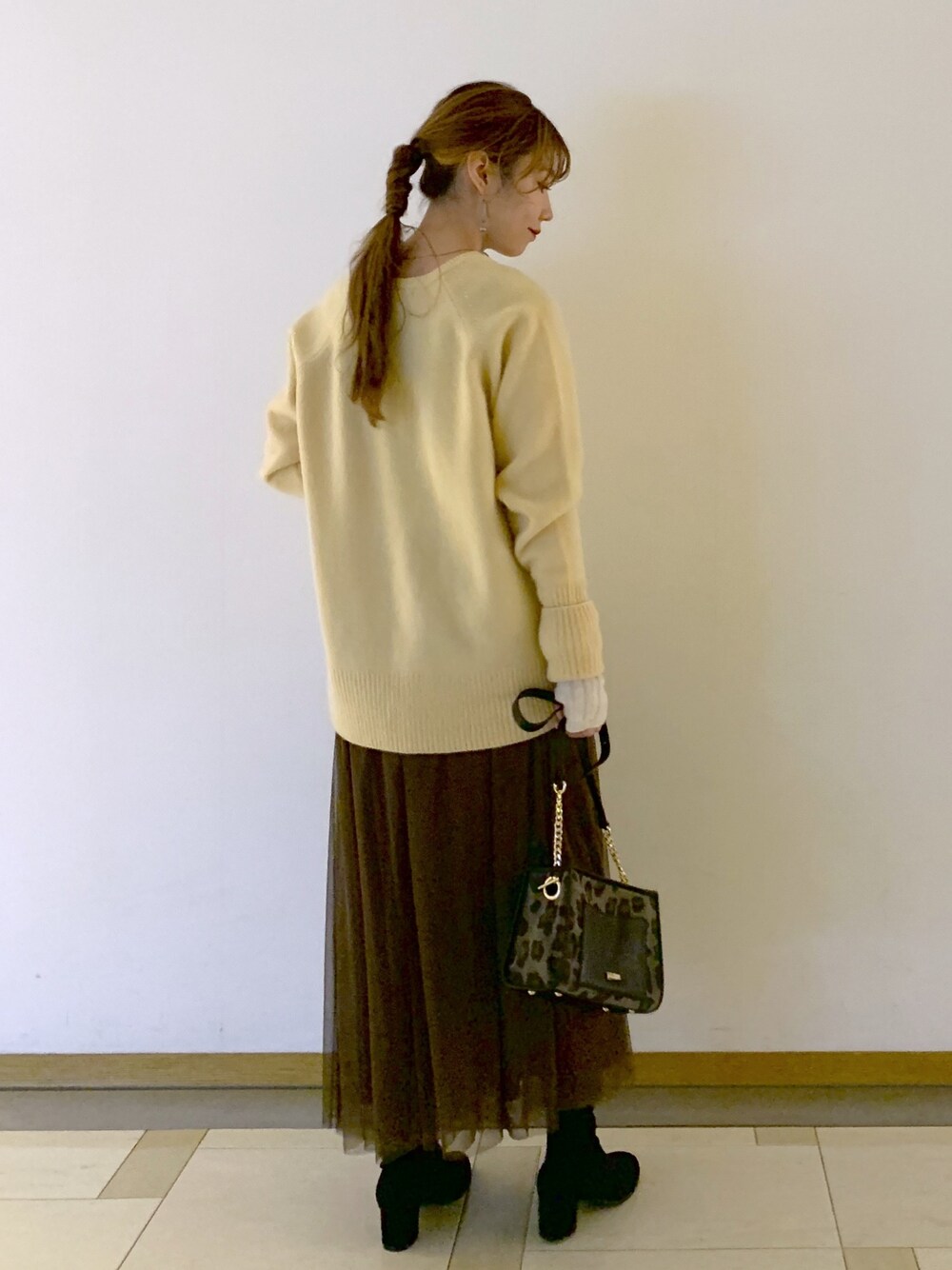 イエロー系のニット/セーター、その他のショルダーバッグ、ブラウン系のスカートを着用したレディースの冬コーディネートの2枚目の写真