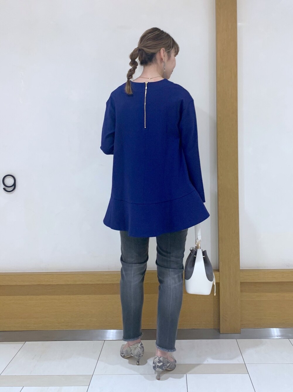 ブルー系のTシャツ/カットソー、グレー系のパンツ、ホワイト系のバッグを着用したレディースの冬コーディネートの2枚目の写真