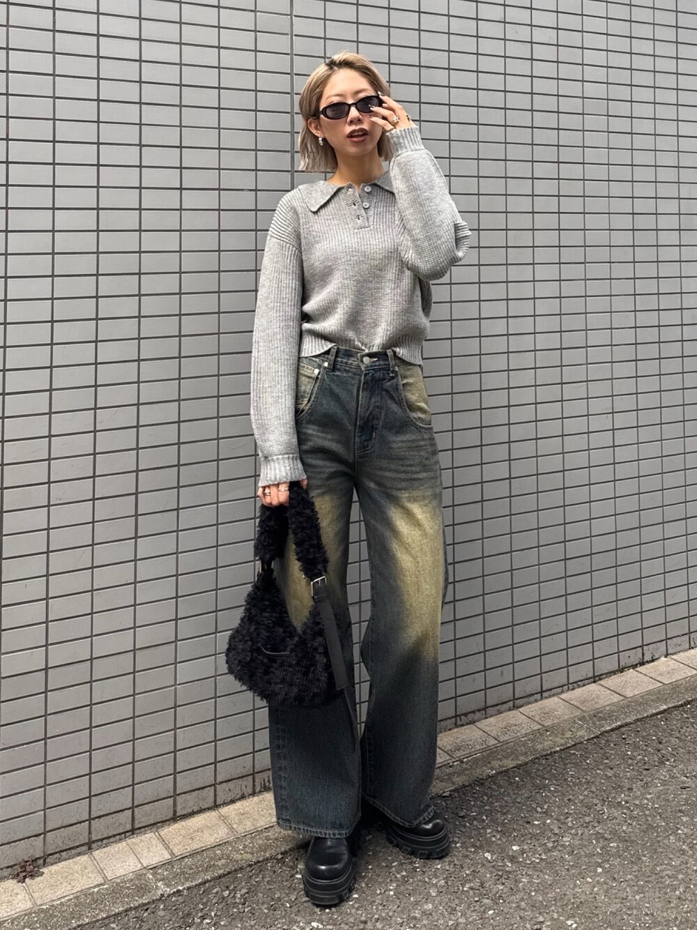 グレー系のニット/セーター、ブルー系のデニムパンツ、ブラック系のショルダーバッグを着用したレディースの冬コーディネートの1枚目の写真