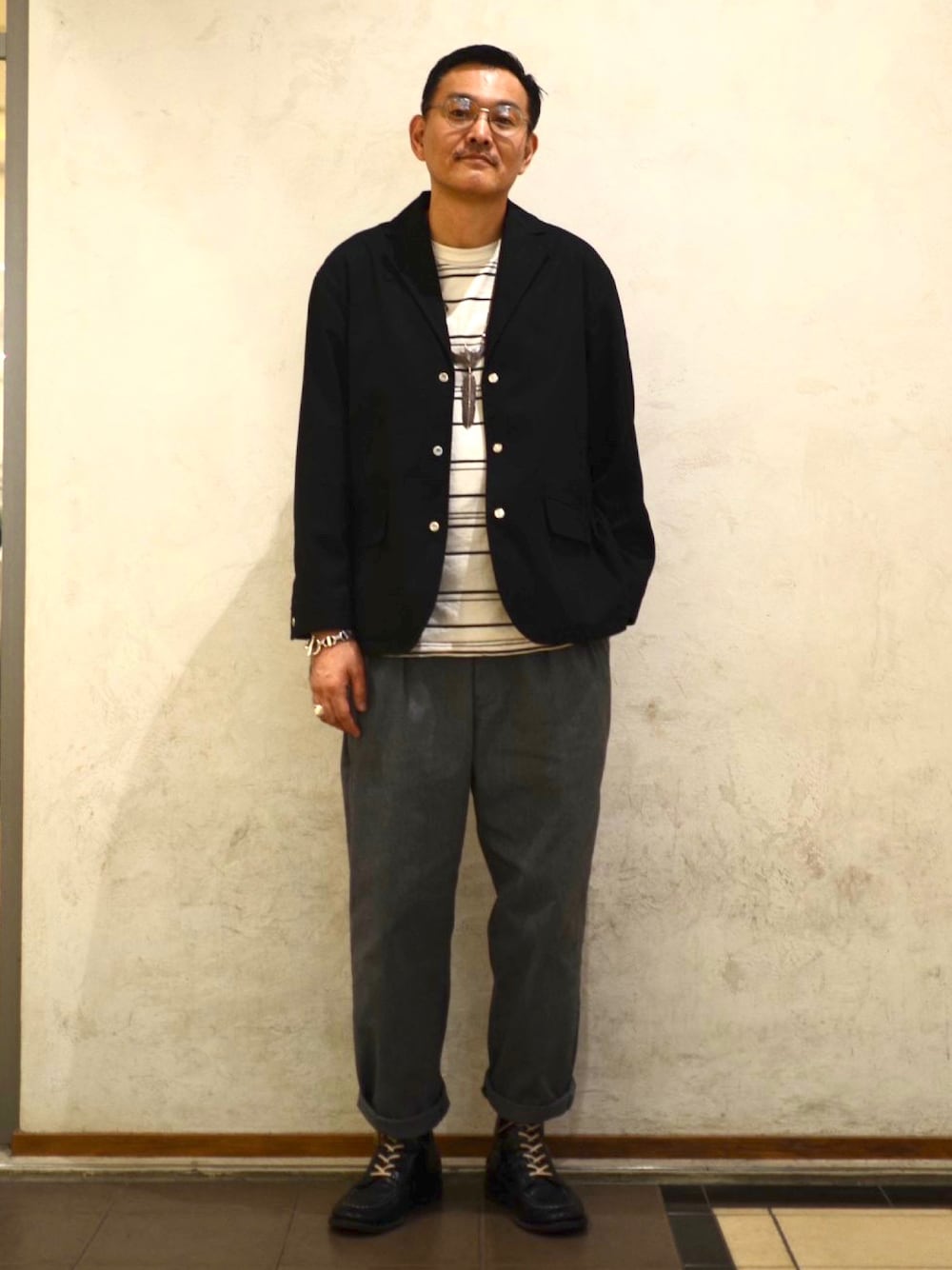 ブラック系のテーラードジャケット、ベージュ系のTシャツ/カットソー、グレー系のチノパンツを着用したメンズの冬コーディネートの1枚目の写真