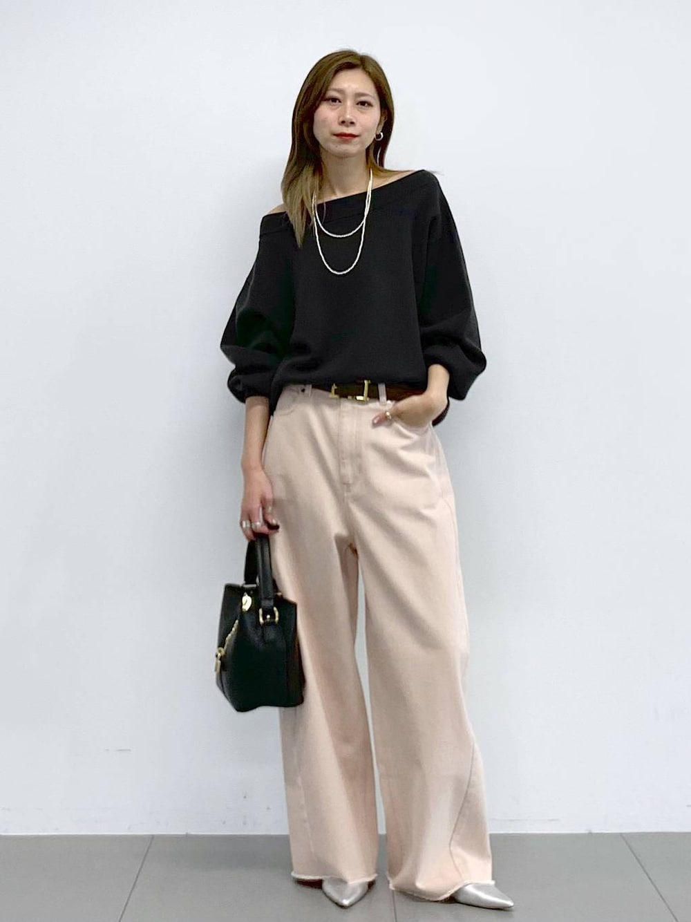 ピンク系のデニムパンツ、シルバー系のパンプス、グレー系のニット/セーターを着用したレディースの冬コーディネートの1枚目の写真