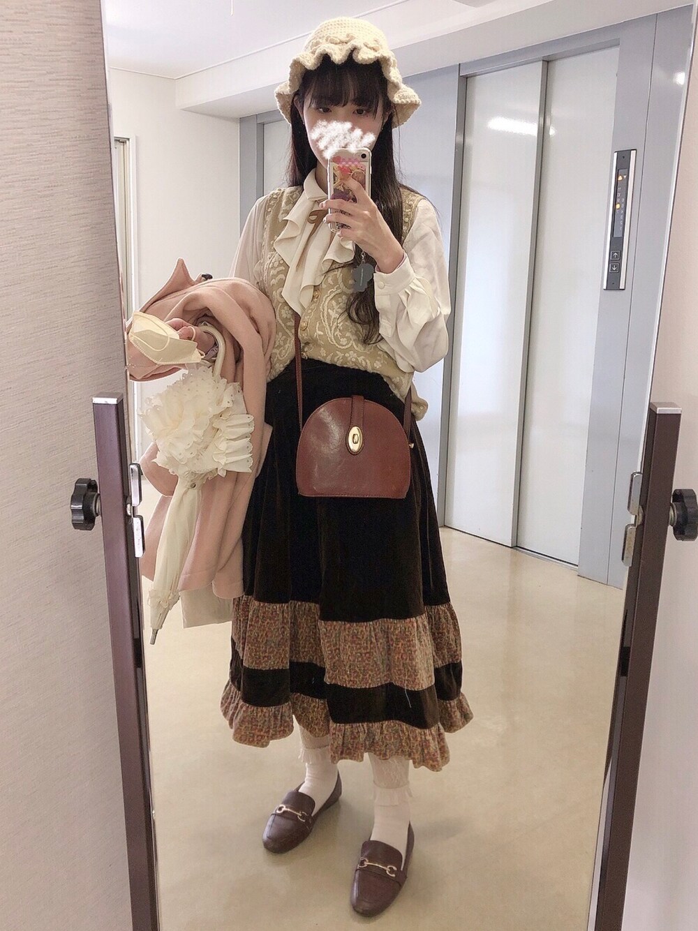 ベージュ系のベスト、ホワイト系のシャツ/ブラウス、ブラウン系のスカートを着用したレディースの冬コーディネートの1枚目の写真