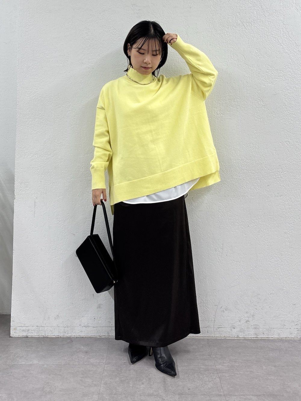 イエロー系のニット/セーター、ホワイト系のシャツ/ブラウス、ブラウン系のスカートを着用したレディースの秋コーディネートの1枚目の写真