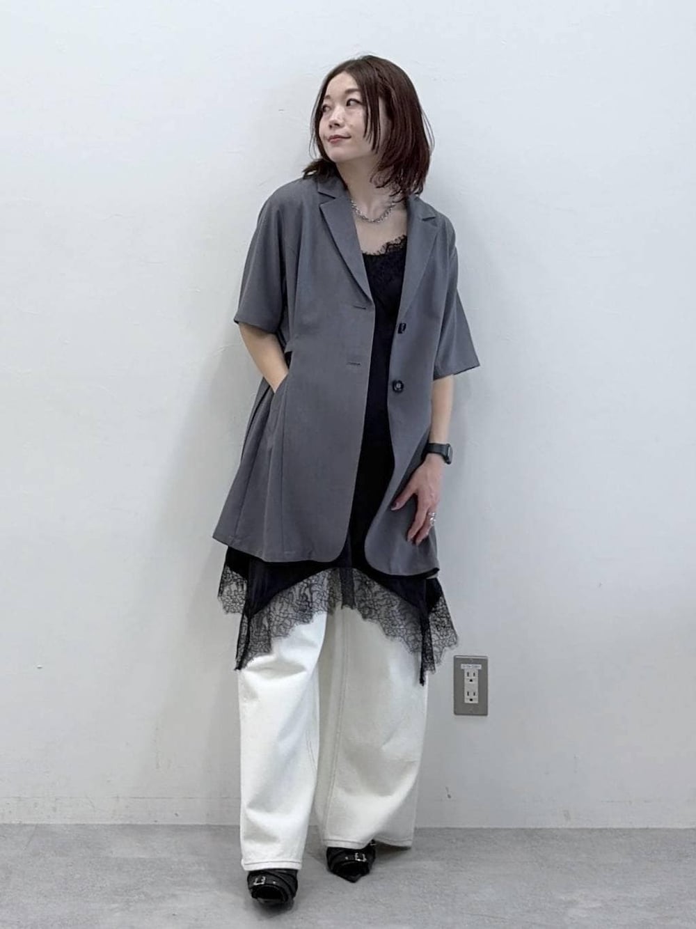 ホワイト系のスラックス、ブラック系のチュニック、ブラック系のサンダルを着用したレディースの春コーディネートの1枚目の写真