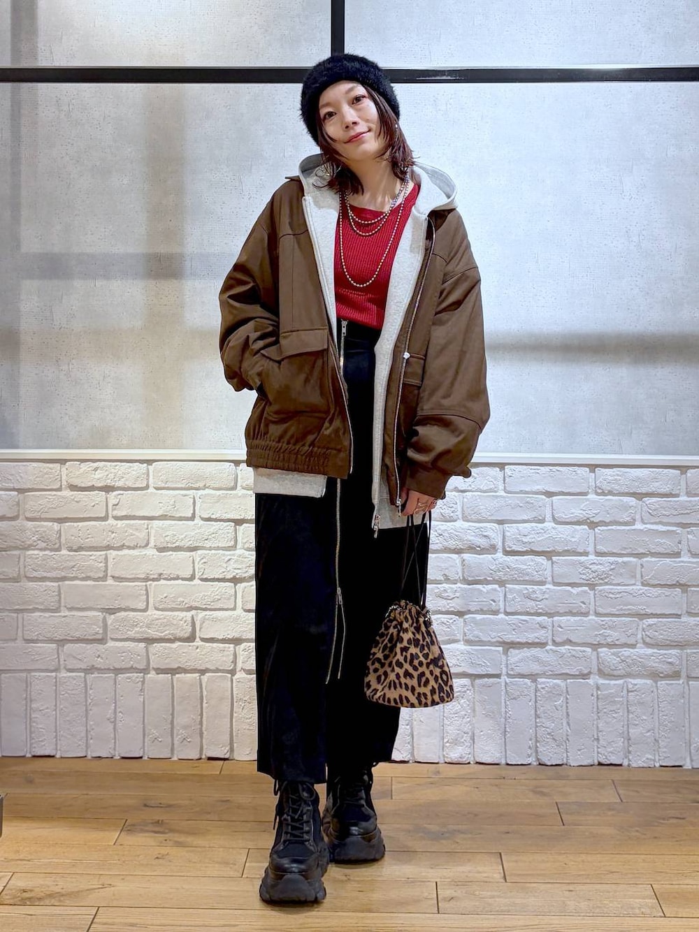 ブラック系のブーツ、ブラウン系のブルゾン、レッド系のニット/セーターを着用したレディースの冬コーディネートの1枚目の写真
