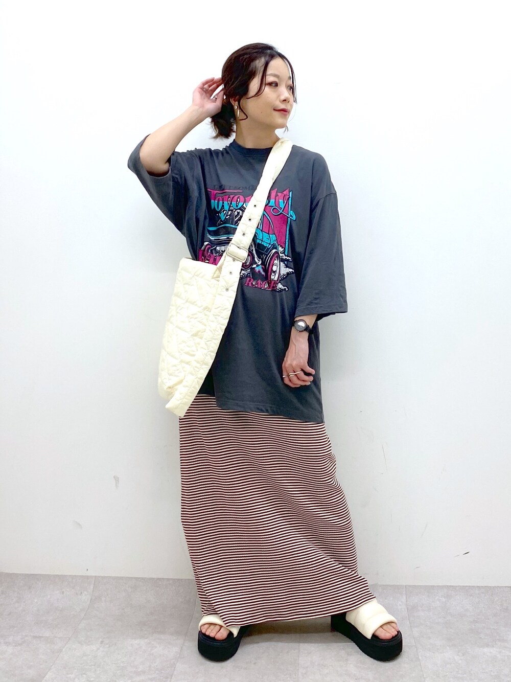 ブラウン系のワンピース、グレー系のTシャツ/カットソー、ホワイト系のショルダーバッグを着用したレディースの春コーディネートの1枚目の写真