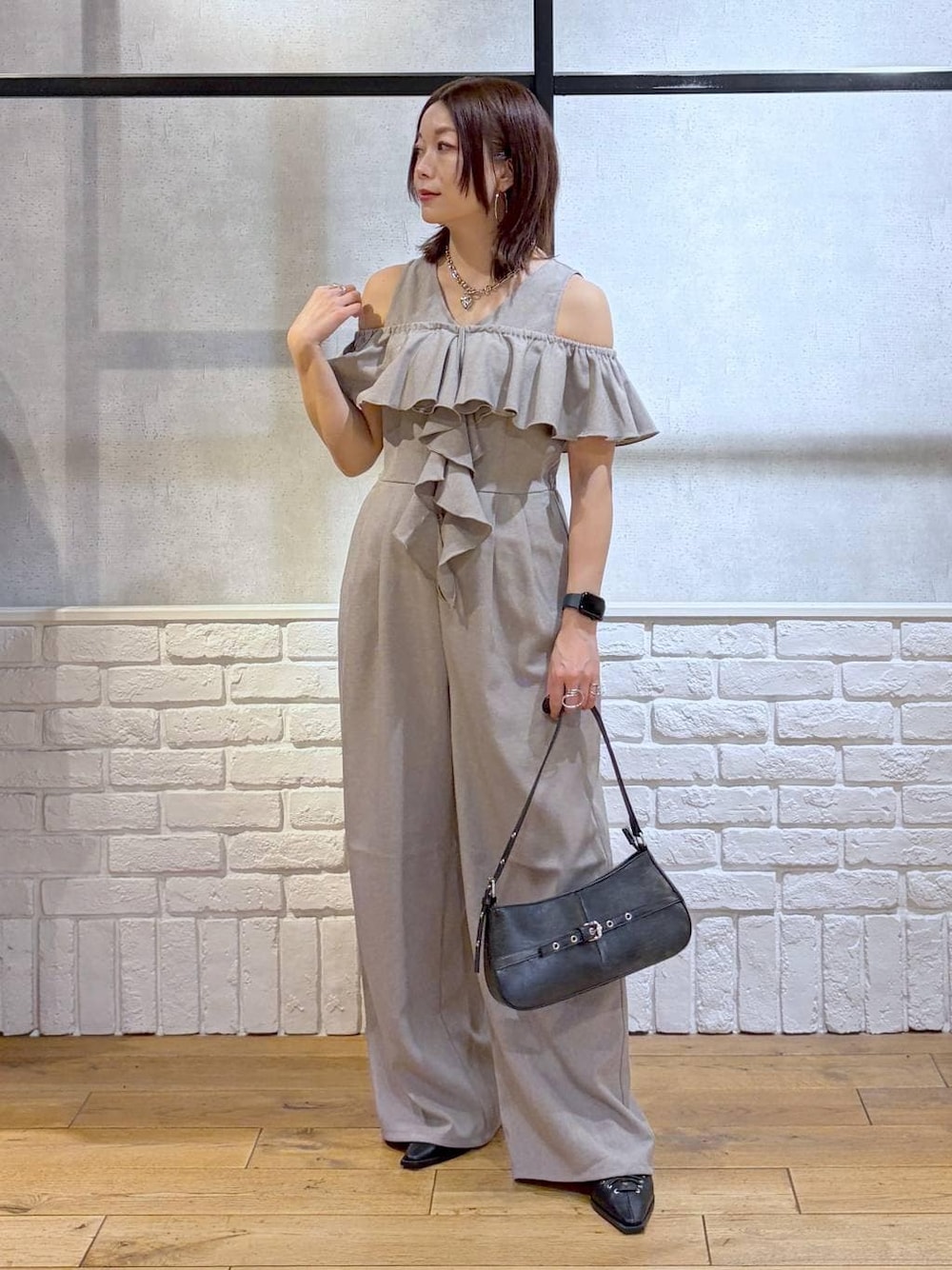 ブラック系のハンドバッグ、ブラック系のサンダル、ベージュ系のサロペット/オーバーオールを着用したレディースの春コーディネートの1枚目の写真