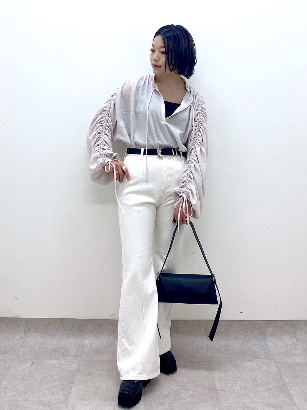 ホワイト系のパンツ、ブラック系のバッグ、ブラック系のローファーを着用したレディースの春コーディネートの1枚目の写真