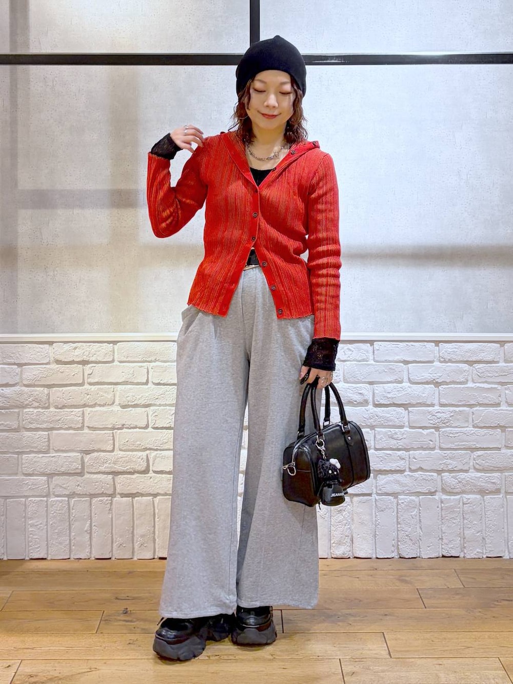ブラック系のスニーカー、ブラック系のボストンバッグ、レッド系のカーディガン/ボレロを着用したレディースの春コーディネートの1枚目の写真