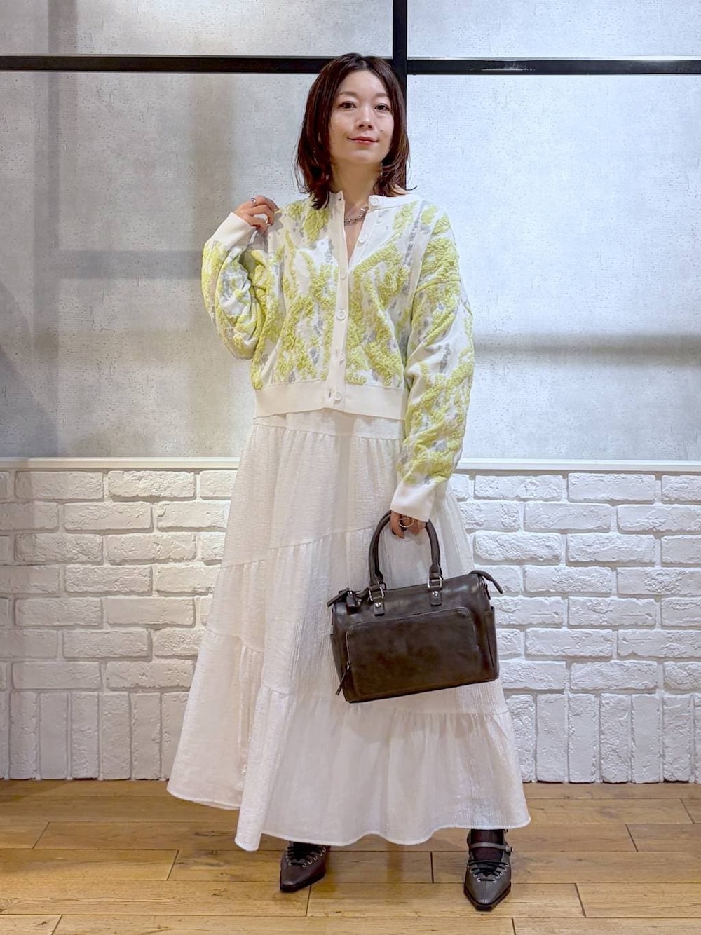 グレー系のショルダーバッグ、ブラウン系のサンダル、ホワイト系のスカートを着用したレディースの冬コーディネートの1枚目の写真