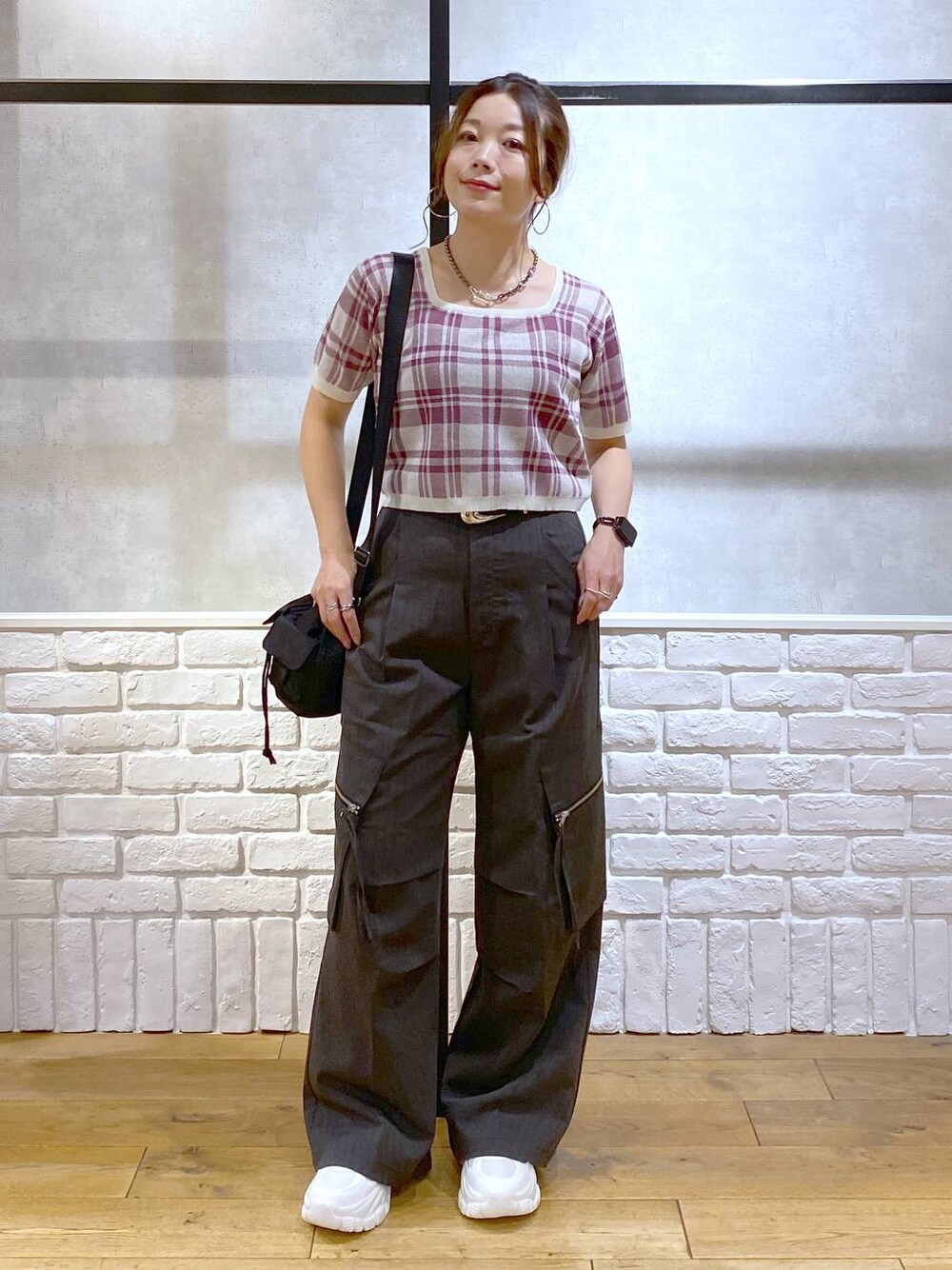 グレー系のカーゴパンツ、ブラック系のショルダーバッグ、ホワイト系のスニーカーを着用したレディースの夏コーディネートの1枚目の写真