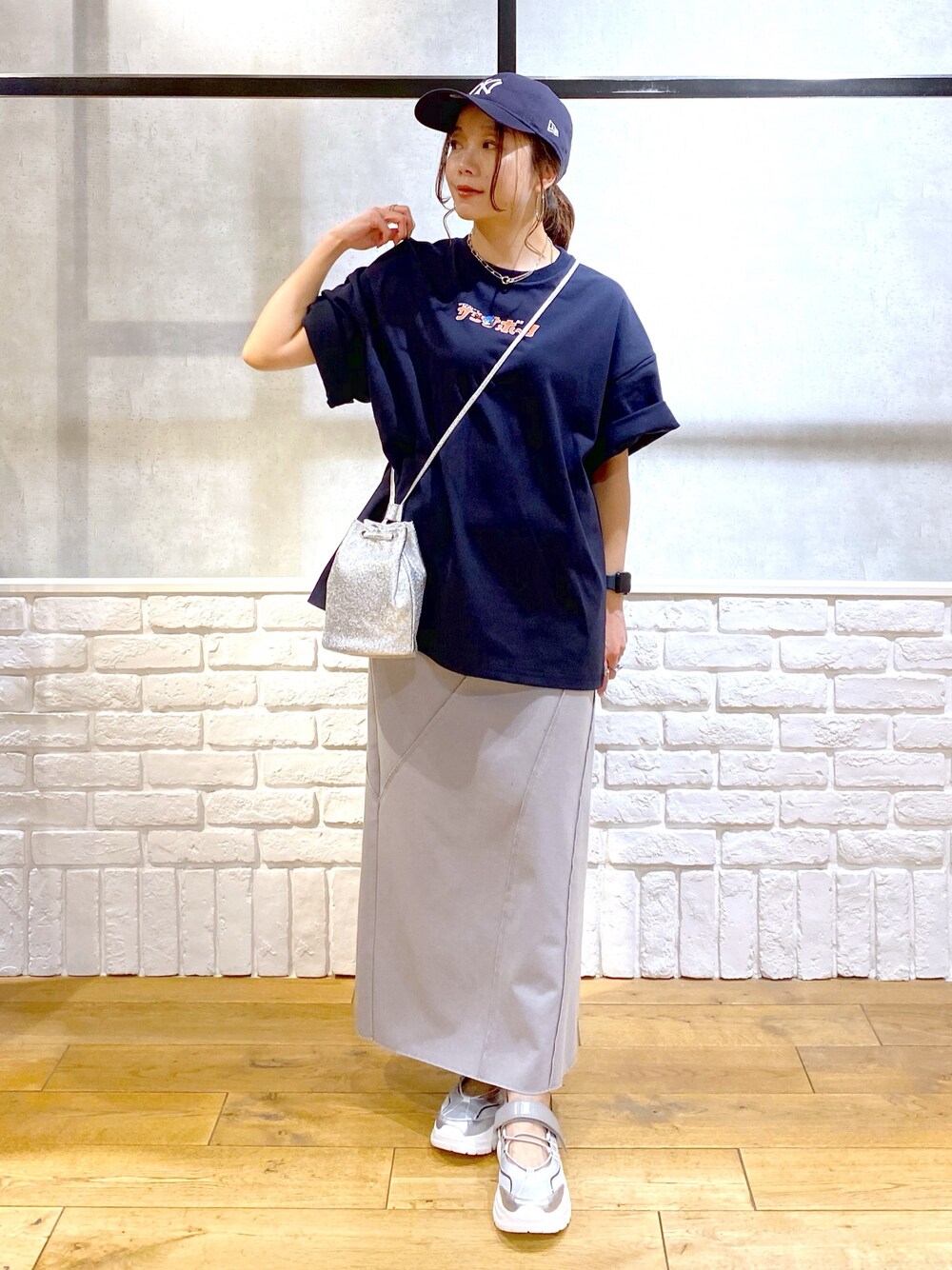 ブルー系のTシャツ/カットソー、グレー系のスカート、グレー系のスニーカーを着用したレディースの春コーディネートの1枚目の写真