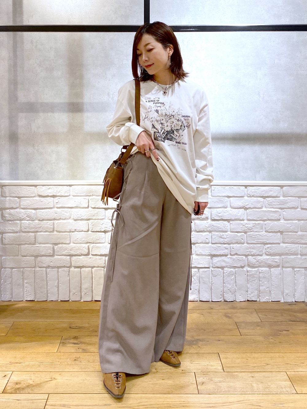 ブラウン系のスラックス、ベージュ系のショルダーバッグ、ブラウン系のパンプスを着用したレディースの春コーディネートの1枚目の写真
