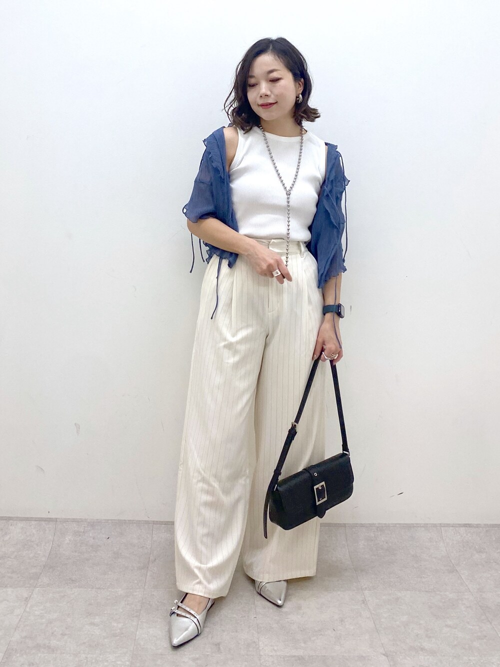 ホワイト系のスラックス、ブラック系のハンドバッグ、シルバー系のパンプスを着用したレディースの夏コーディネートの1枚目の写真