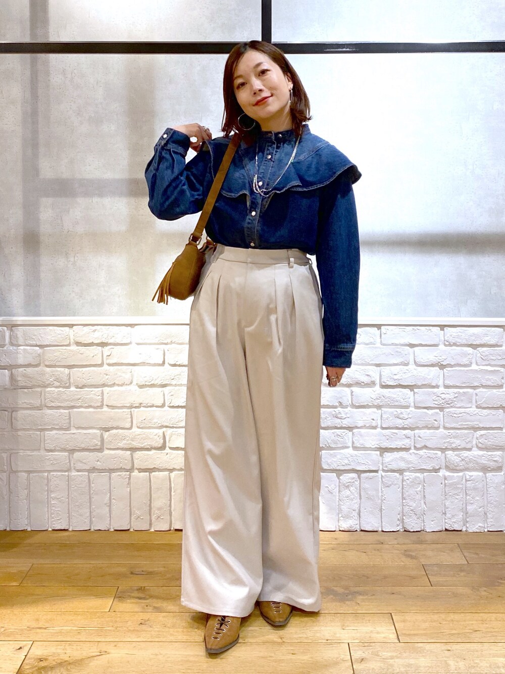 ブルー系のシャツ/ブラウス、ベージュ系のショルダーバッグ、ベージュ系のスラックスを着用したレディースの春コーディネートの1枚目の写真