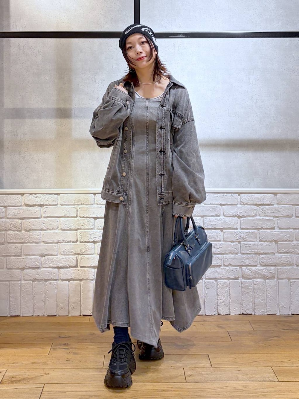 ブラック系のスニーカー、ブルー系のハンドバッグ、ブラック系のブルゾンを着用したレディースの冬コーディネートの1枚目の写真