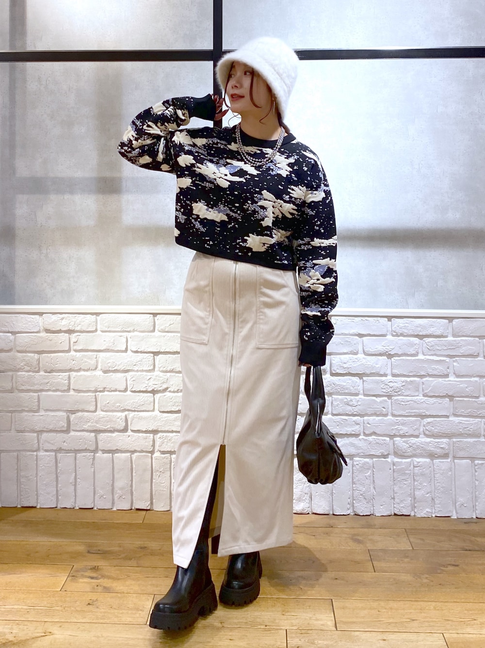 ブラック系のニット/セーター、ブラック系のハンドバッグ、ブラック系のブーツを着用したレディースの冬コーディネートの1枚目の写真