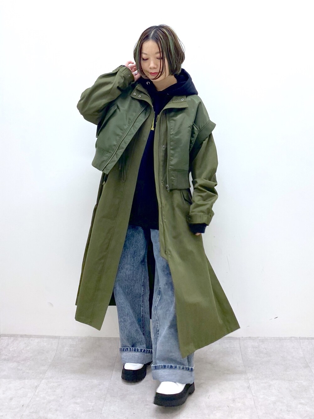 グリーン系のモッズコート、ブラック系のトップス、ブルー系のデニムパンツを着用したレディースの冬コーディネートの1枚目の写真