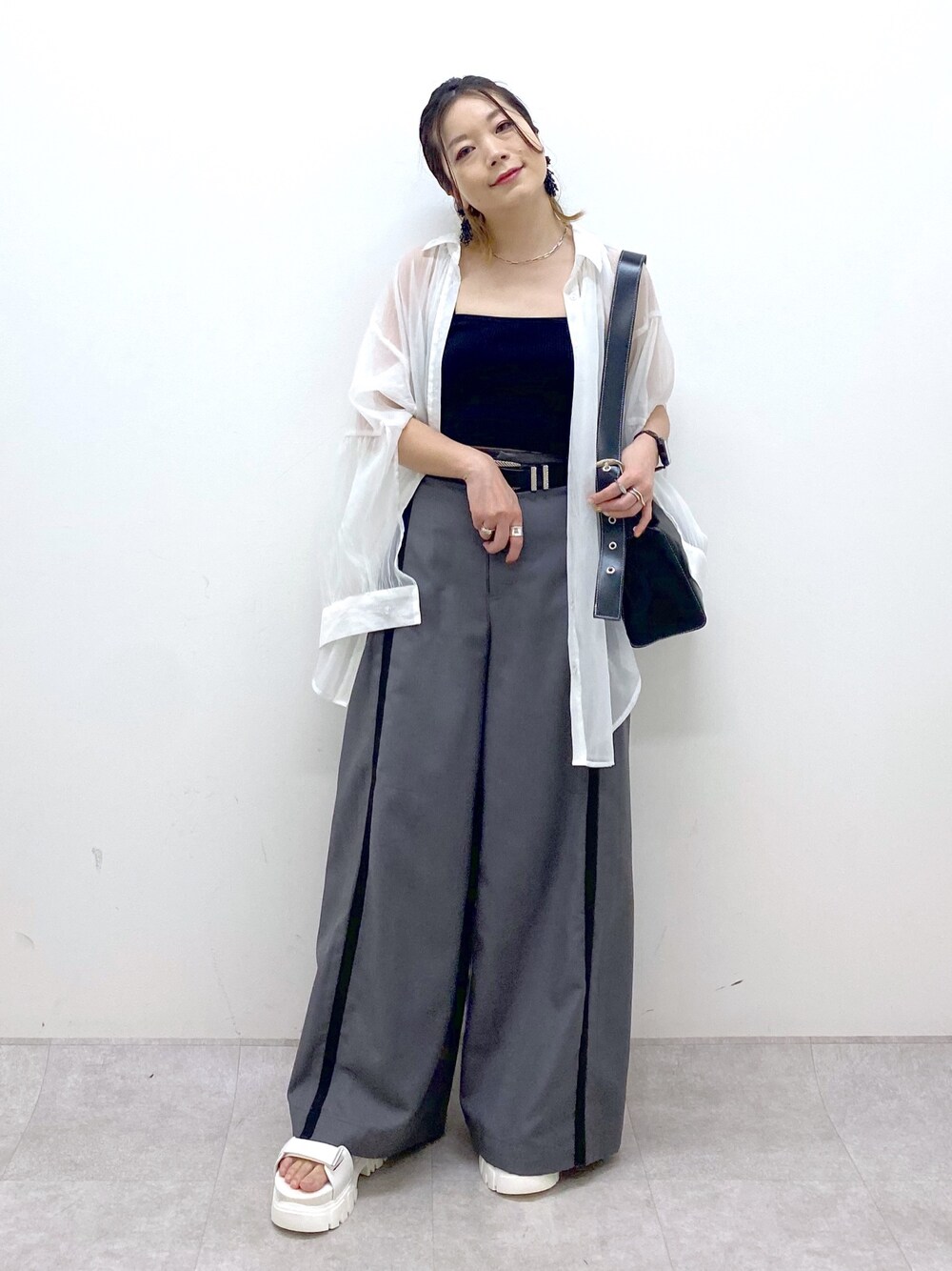 グレー系のスラックス、ブラック系のキャミソール、ブラック系のショルダーバッグを着用したレディースの夏コーディネートの1枚目の写真