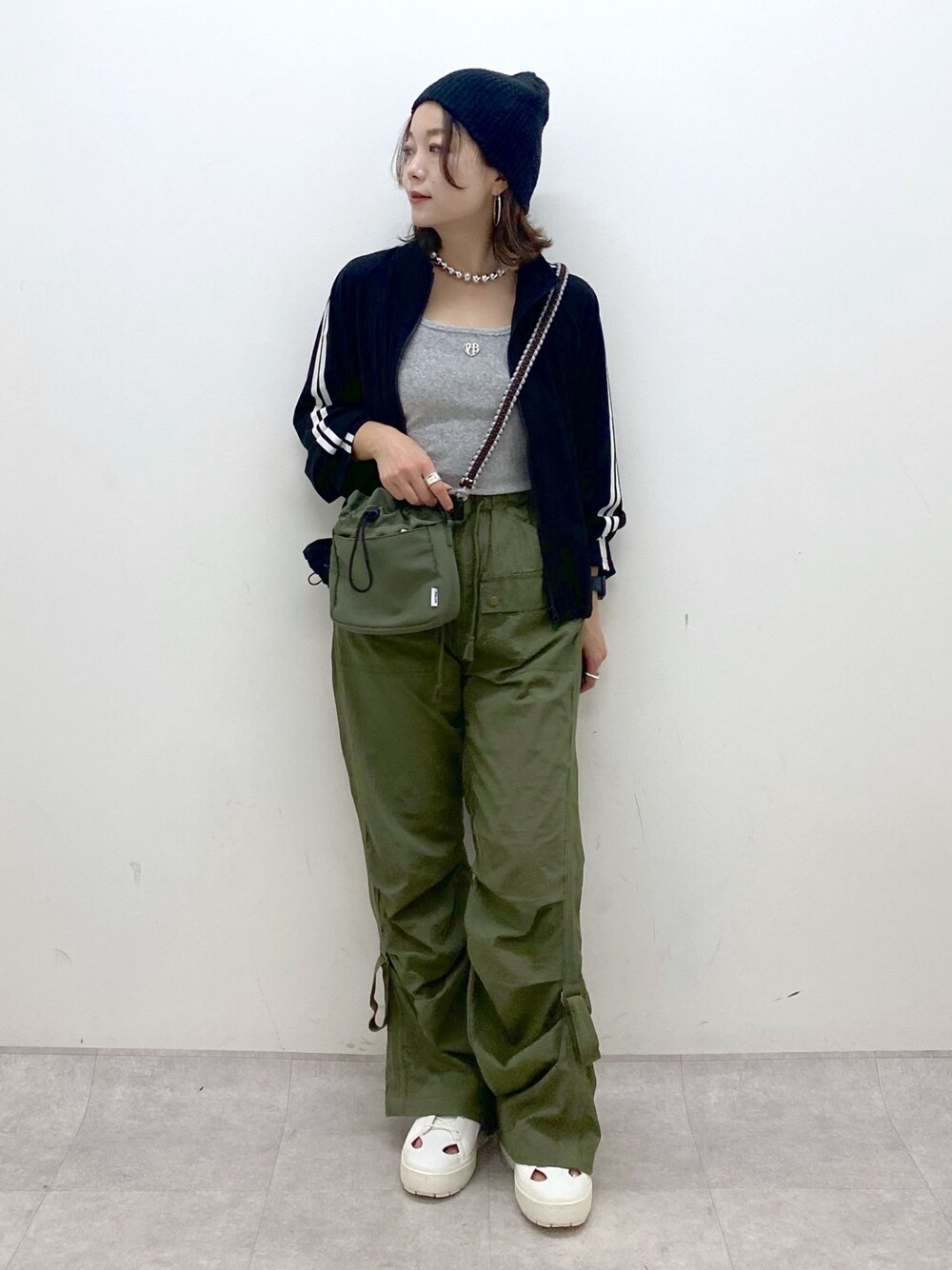 グリーン系のカーゴパンツ、ホワイト系のスニーカー、グリーン系のショルダーバッグを着用したレディースの夏コーディネートの1枚目の写真