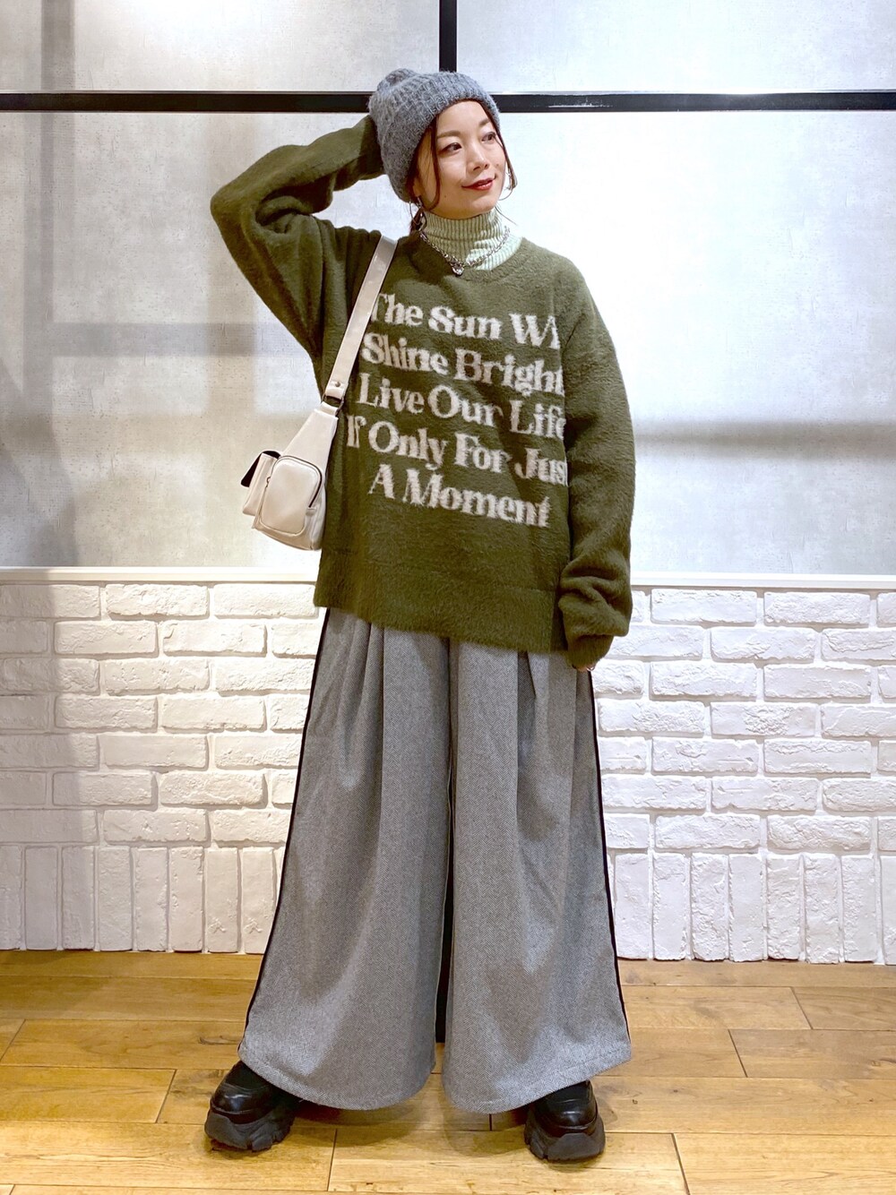 ブラック系のスラックス、グリーン系のTシャツ/カットソー、ブラック系のブーツを着用したレディースの冬コーディネートの1枚目の写真