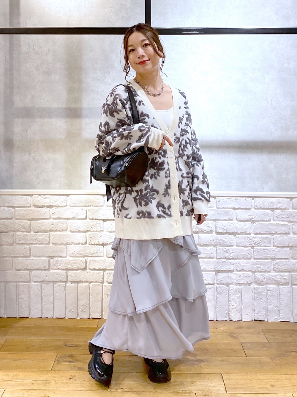 ブラック系のショルダーバッグ、ホワイト系のカーディガン/ボレロ、ホワイト系のキャミソールを着用したレディースの春コーディネートの1枚目の写真