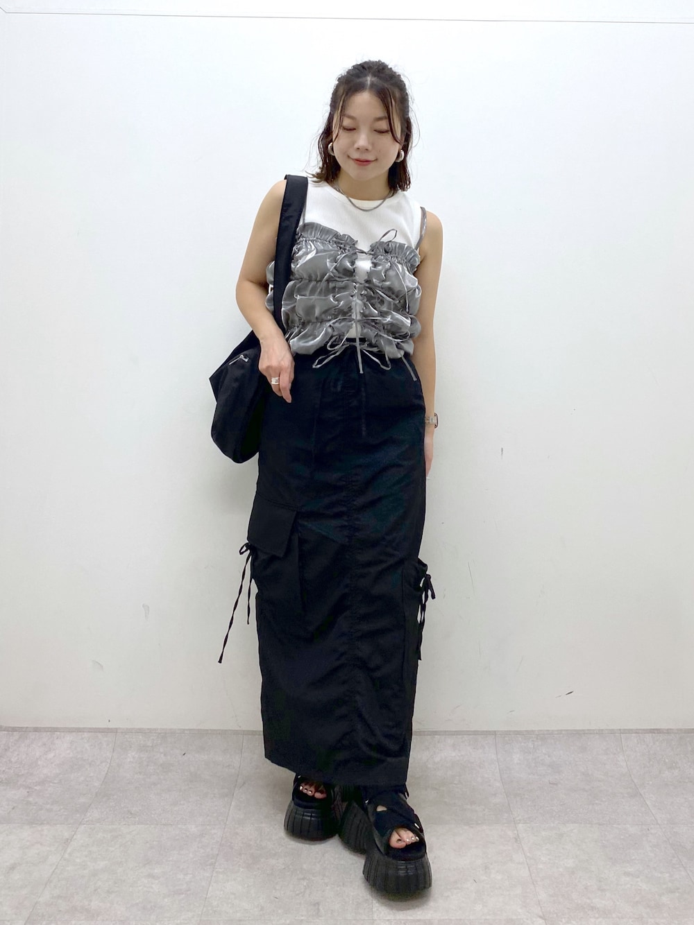 ブラック系のスニーカー、ブラック系のスカート、ブラック系のショルダーバッグを着用したレディースの夏コーディネートの1枚目の写真