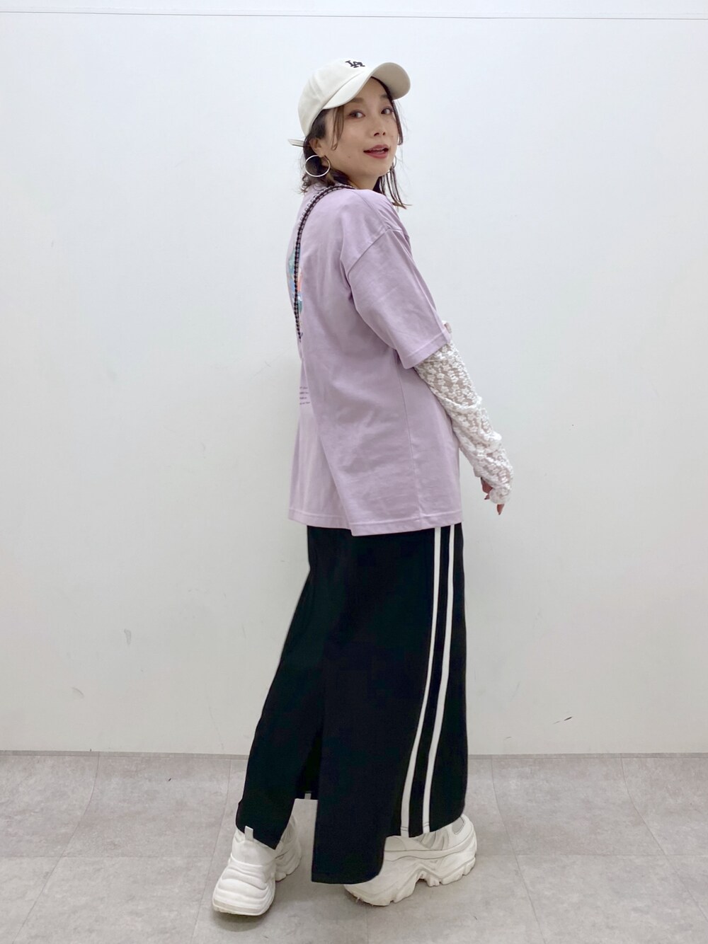 ブラック系のスカート、ホワイト系のスニーカー、ホワイト系のTシャツ/カットソーを着用したレディースの夏コーディネートの1枚目の写真