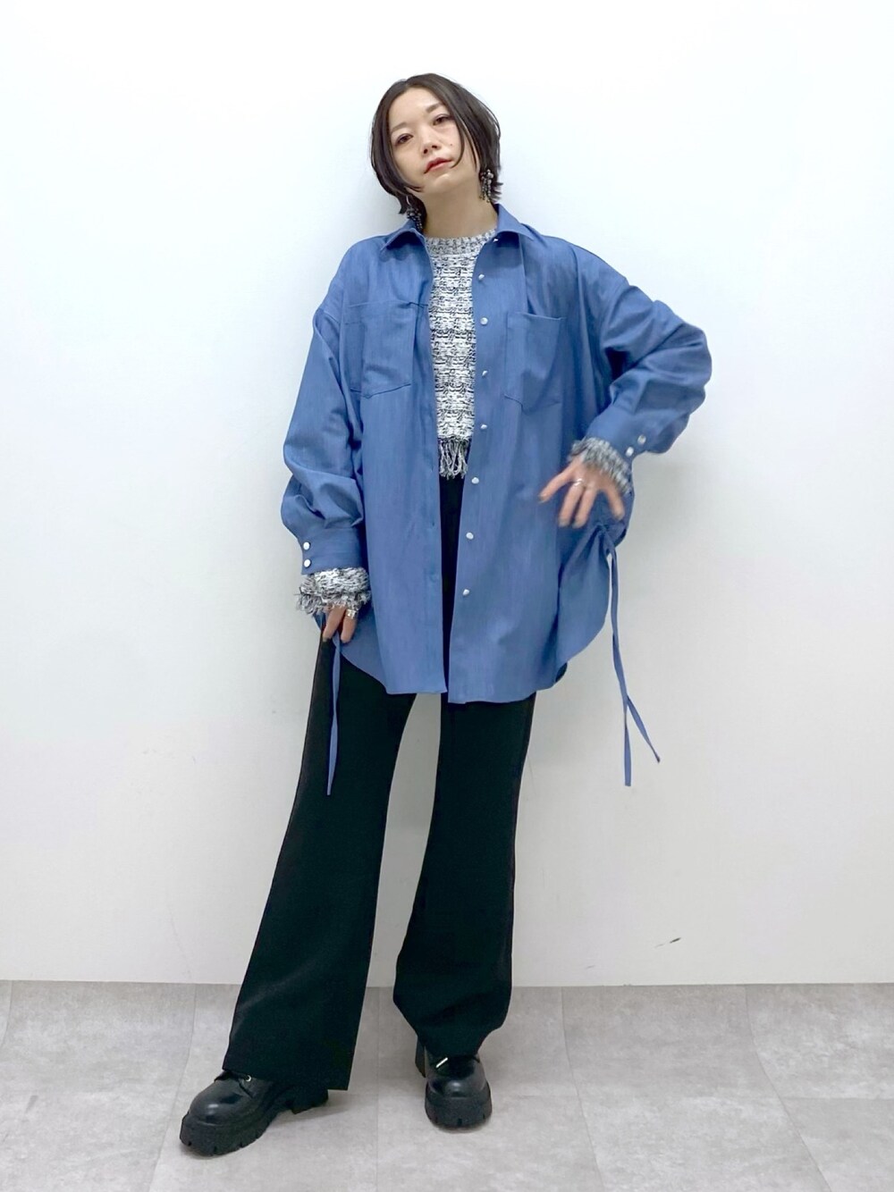 ブラック系のデニムパンツ、ブルー系のシャツ/ブラウス、ホワイト系のニット/セーターを着用したレディースの冬コーディネートの1枚目の写真