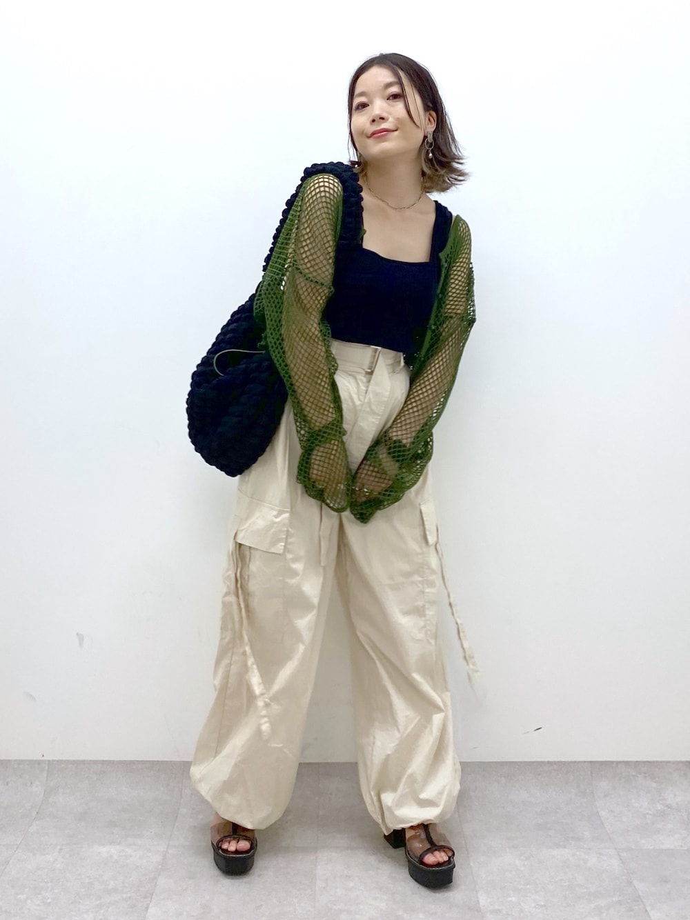 ホワイト系のカーゴパンツ、ブラック系のトップス、グリーン系のTシャツ/カットソーを着用したレディースの夏コーディネートの1枚目の写真