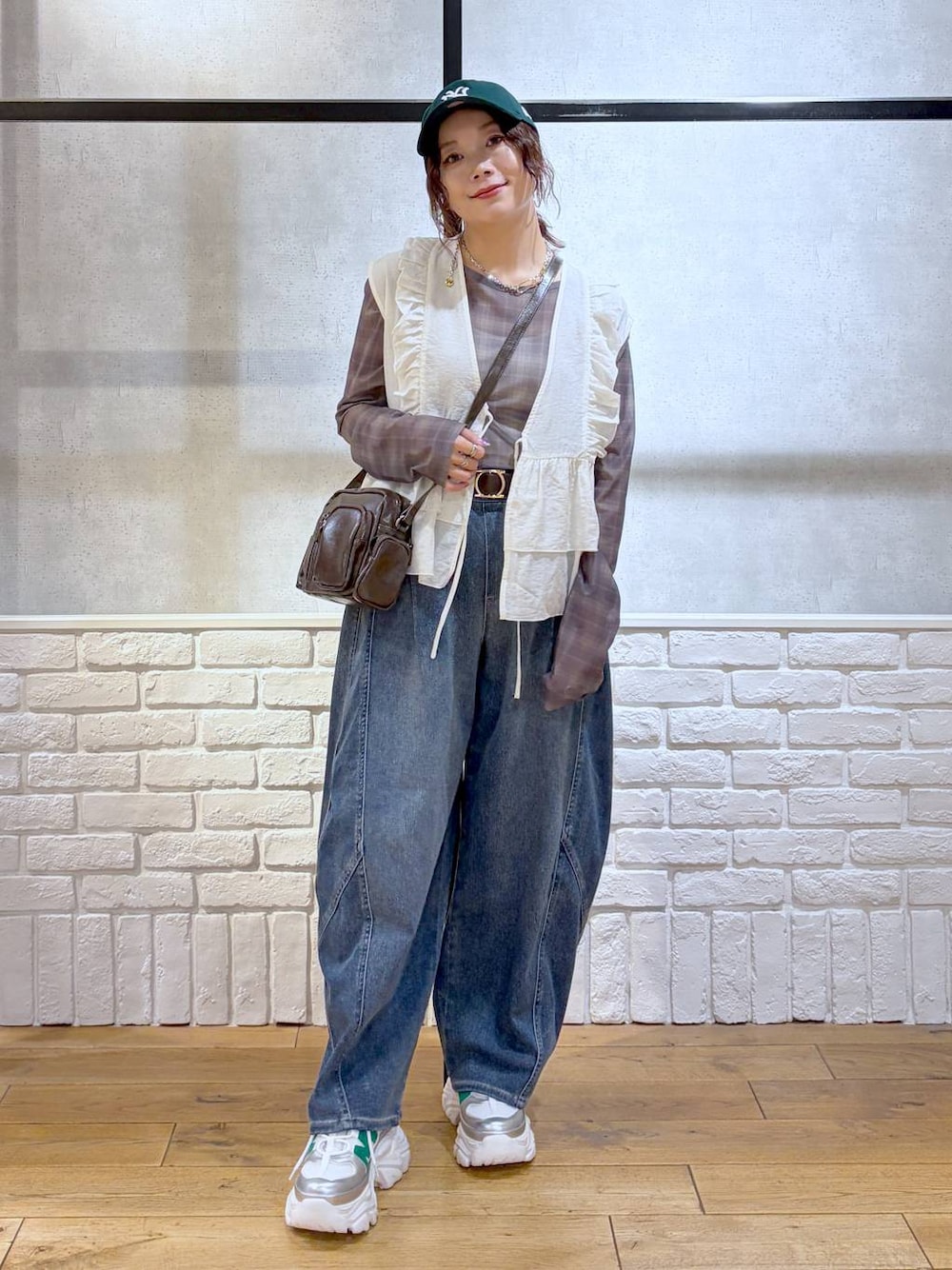 ホワイト系のスニーカー、ブラウン系のショルダーバッグ、ブルー系のデニムパンツを着用したレディースの春コーディネートの1枚目の写真