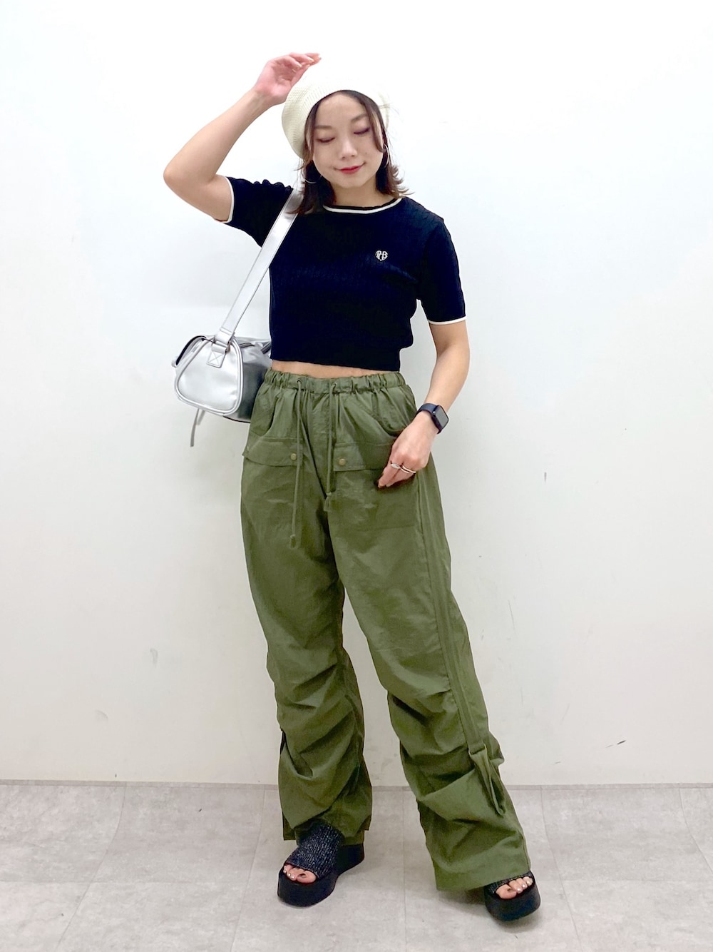 グリーン系のカーゴパンツ、ブラック系のサンダル、シルバー系のショルダーバッグを着用したレディースの夏コーディネートの1枚目の写真