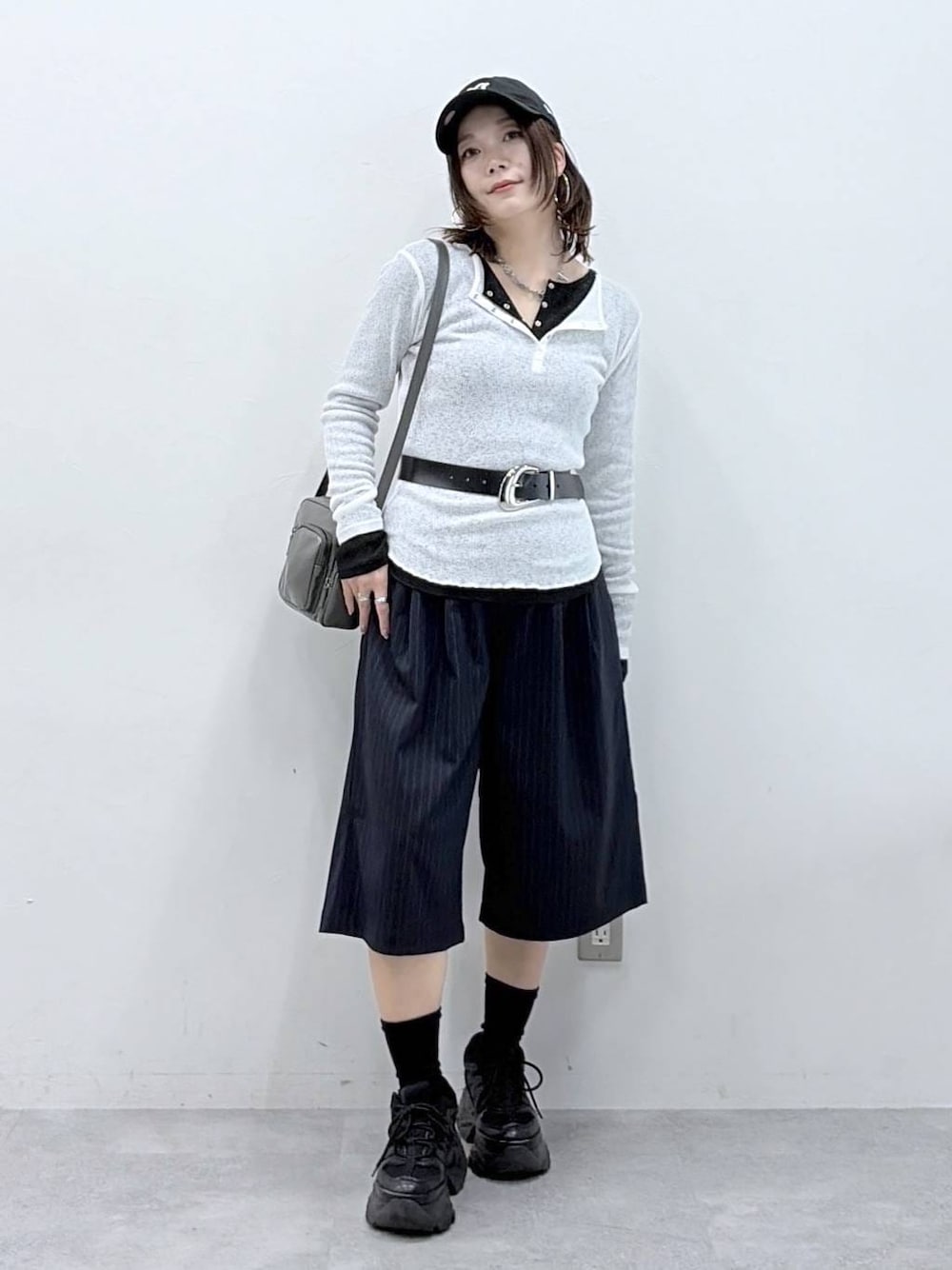 ブラック系のスニーカー、グレー系のショルダーバッグ、ブラック系のTシャツ/カットソーを着用したレディースの春コーディネートの1枚目の写真