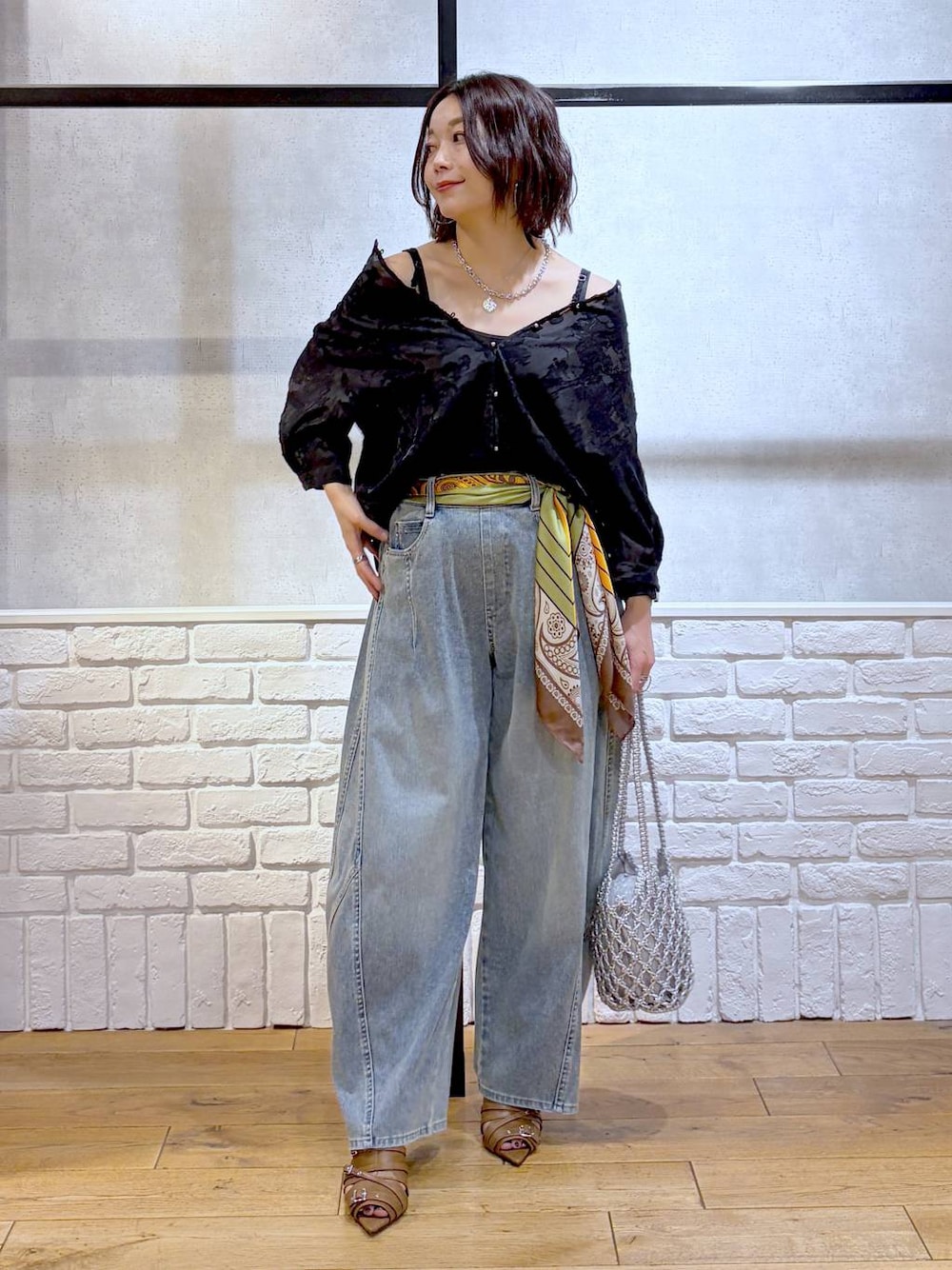 シルバー系のショルダーバッグ、ブルー系のデニムパンツ、イエロー系のサンダルを着用したレディースの夏コーディネートの1枚目の写真