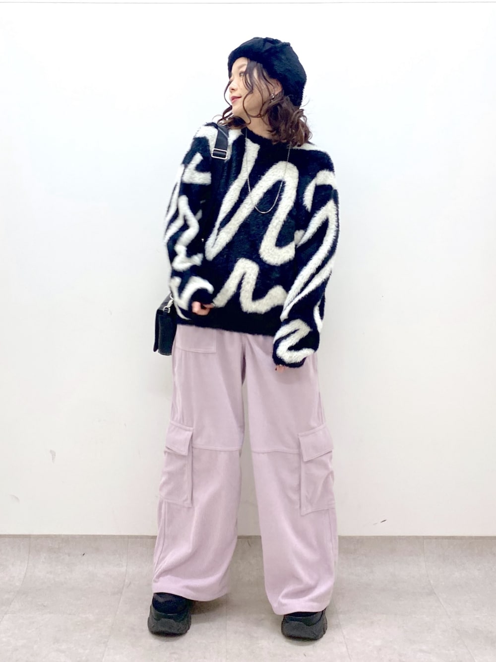 ピンク系のカーゴパンツ、ブラック系のニット/セーター、ブラック系のショルダーバッグを着用したレディースの冬コーディネートの1枚目の写真