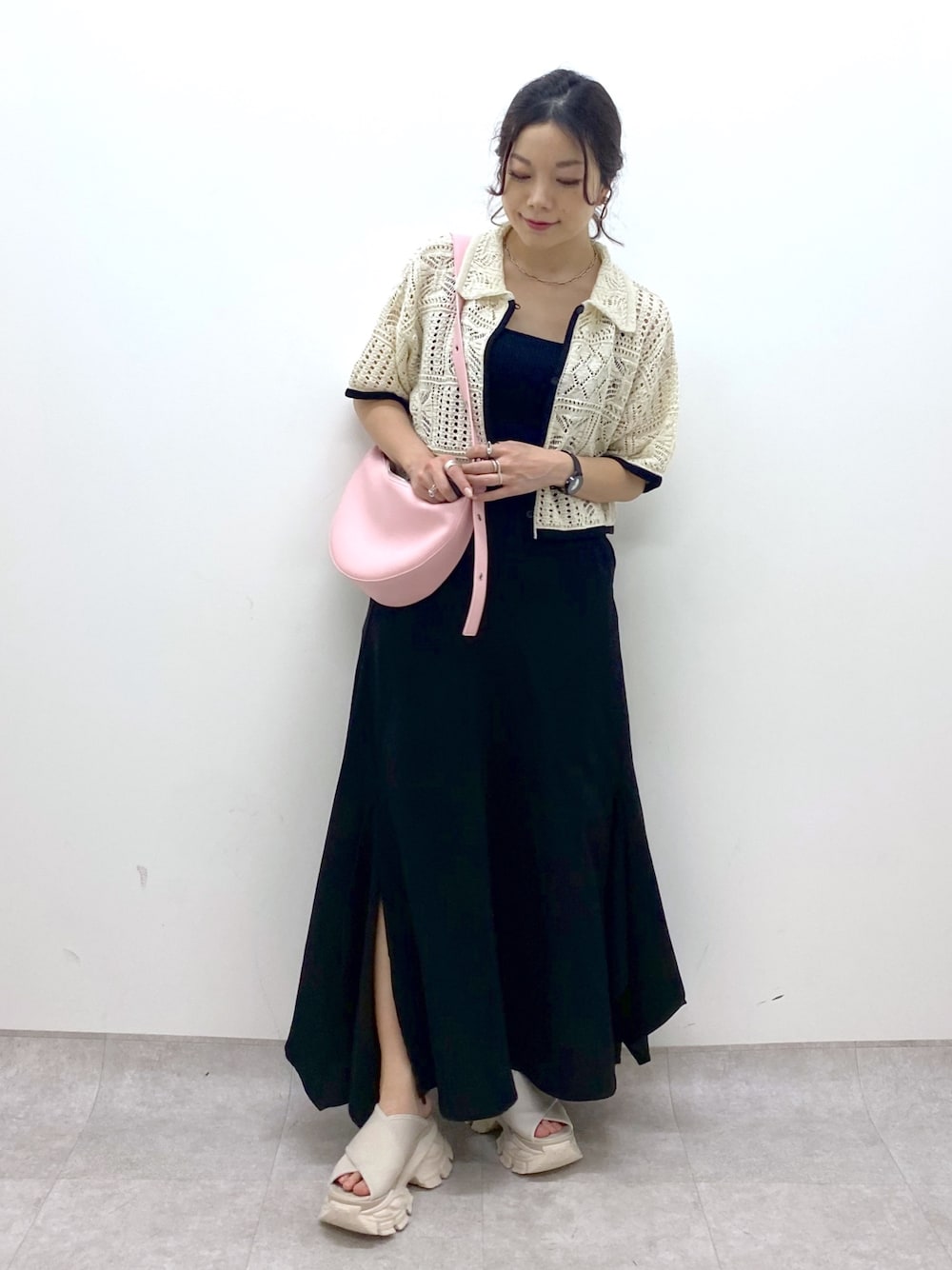 ブラック系のスカート、ホワイト系のカーディガン/ボレロ、ピンク系のショルダーバッグを着用したレディースの夏コーディネートの1枚目の写真