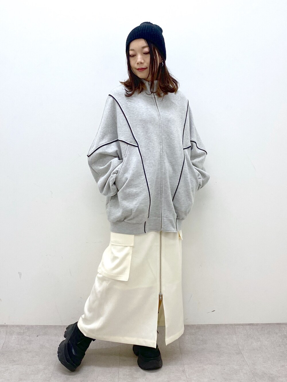 ホワイト系のスカート、ブラック系のスニーカー、グレー系のスウェットを着用したレディースの冬コーディネートの1枚目の写真